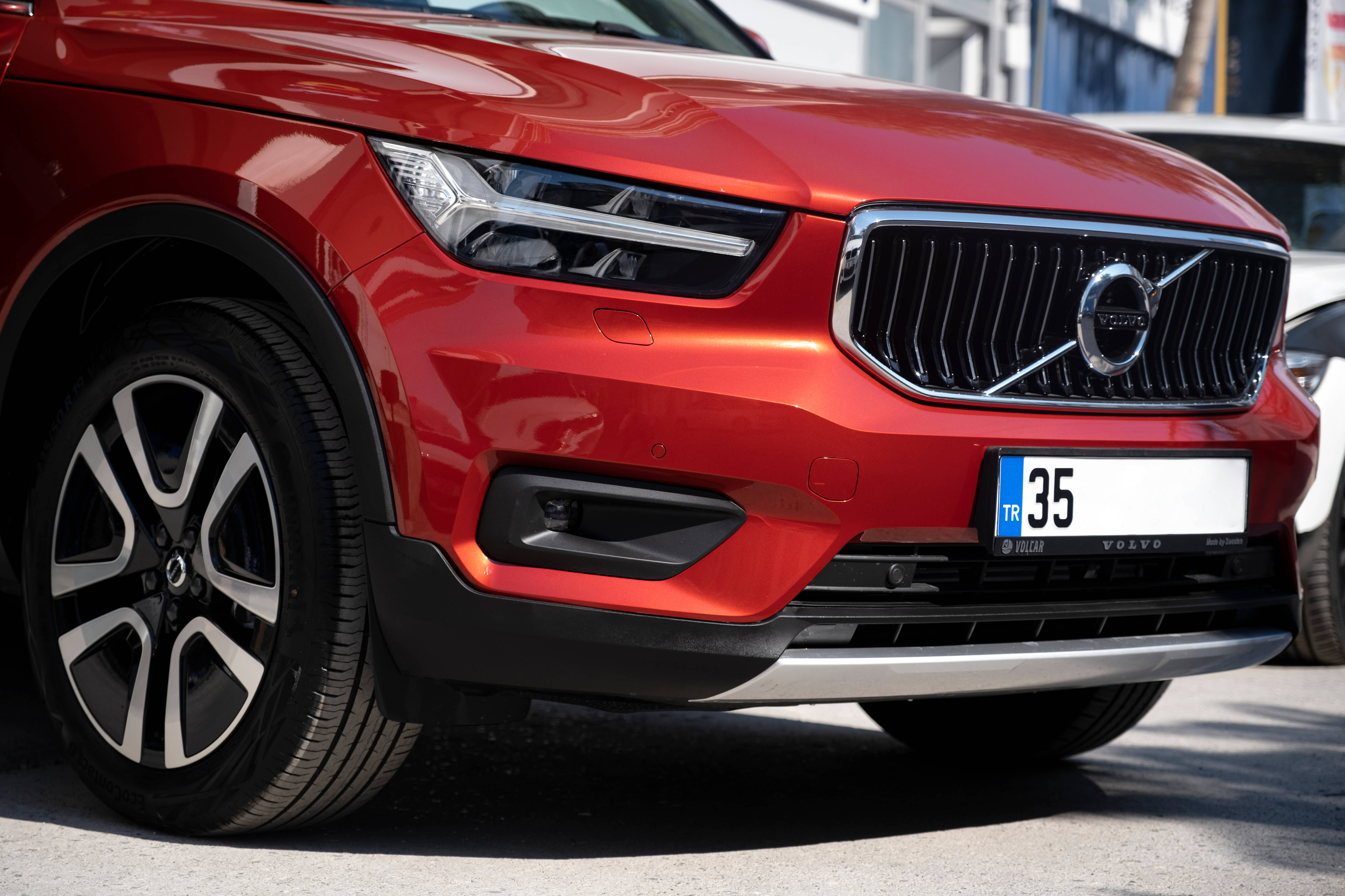 Mercedes Amg 桌布 壁紙 — 紅色沃爾沃SUV車頭特寫，在明亮日光下展示時尚頭燈、鍍鉻格柵和時尚合金輪圈。