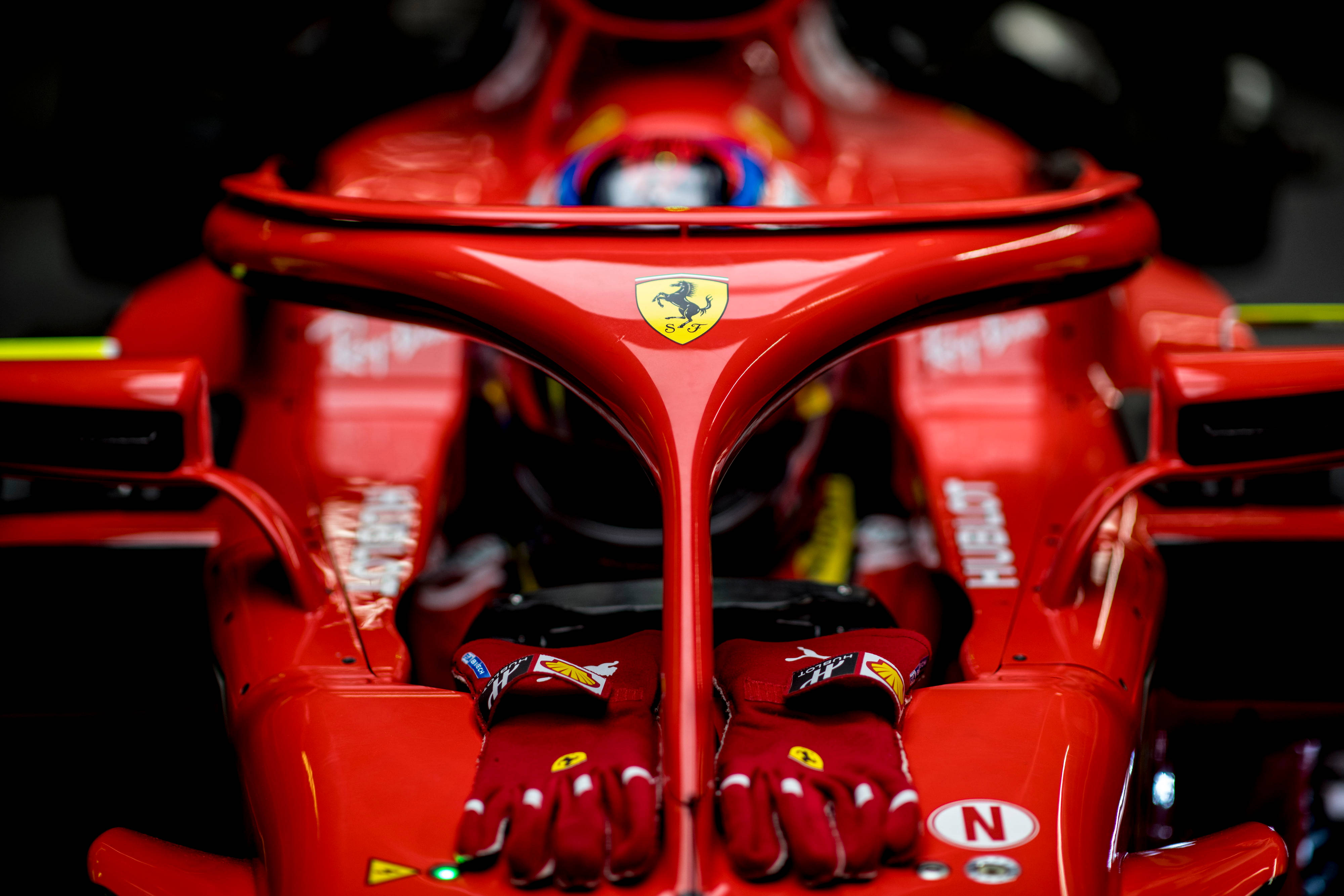 F1 桌布 壁紙 — 紅色法拉利F1賽車駕駛艙的特寫，配有賽車手套和標誌性的躍馬標誌。