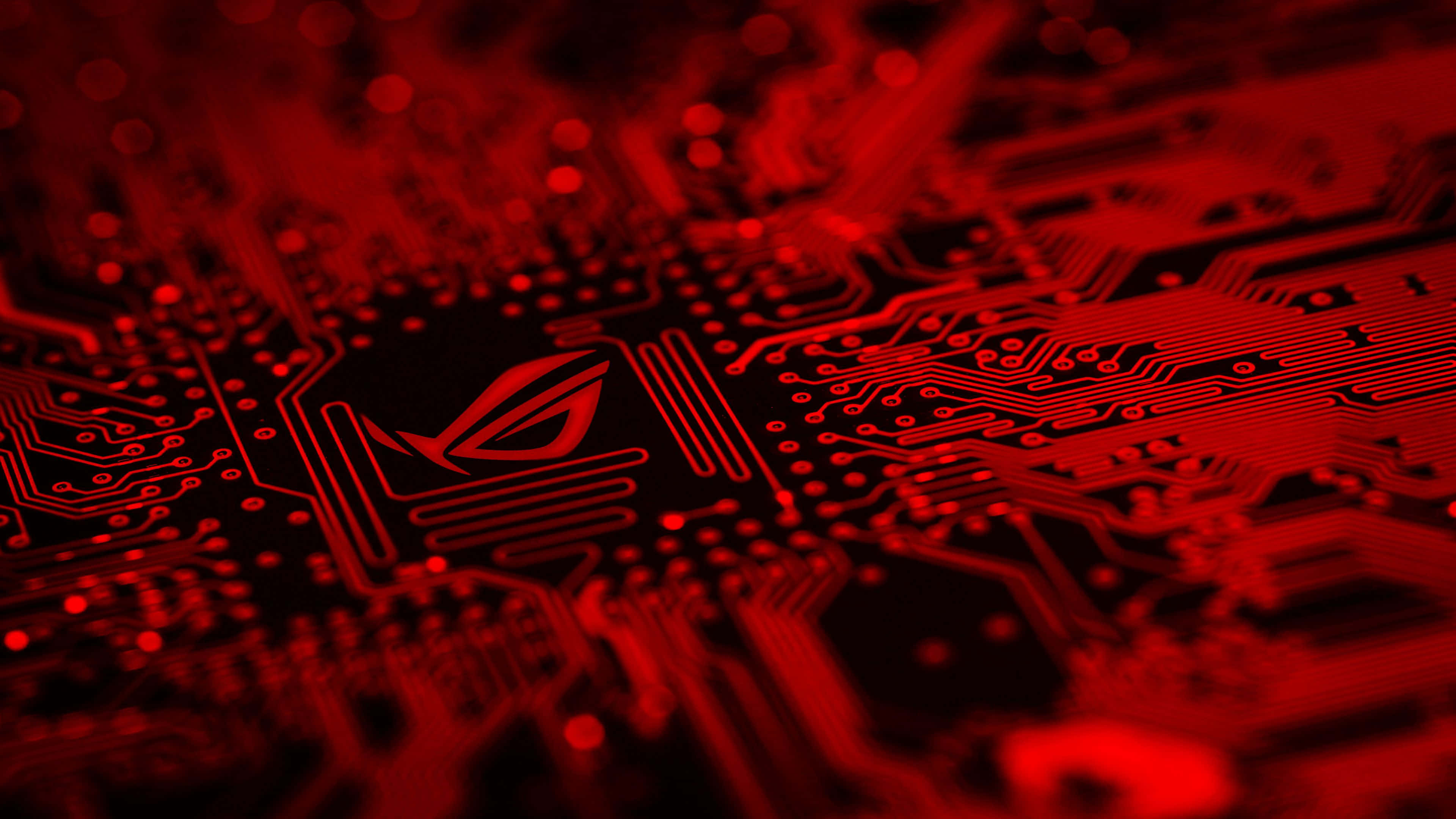 華碩 ROG 桌布 壁紙 — 紅色照明電路板的特寫，ROG 標誌在黑暗路徑上發光。