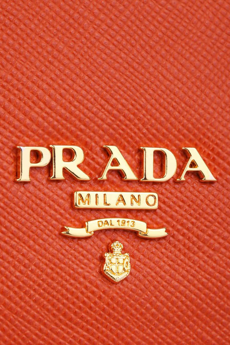 Prada 桌布 壁紙 — 紅色紋理Prada皮革手袋特寫，帶有金色標誌和徽章圖案。