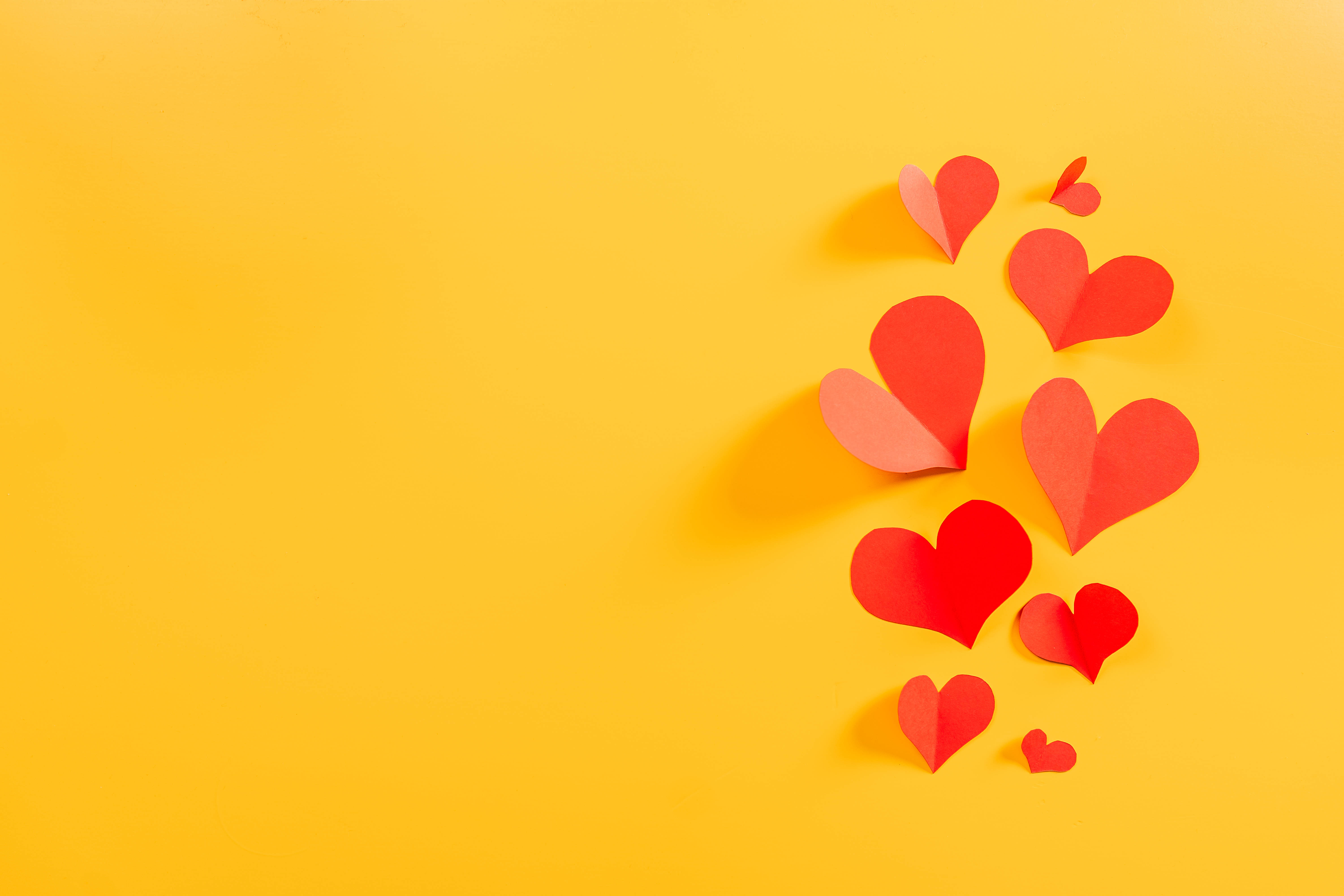 Aesthetic Heart 桌布 壁紙 — 紅色紙心在鮮黃色背景上漂浮，呈現俏皮的散落排列。