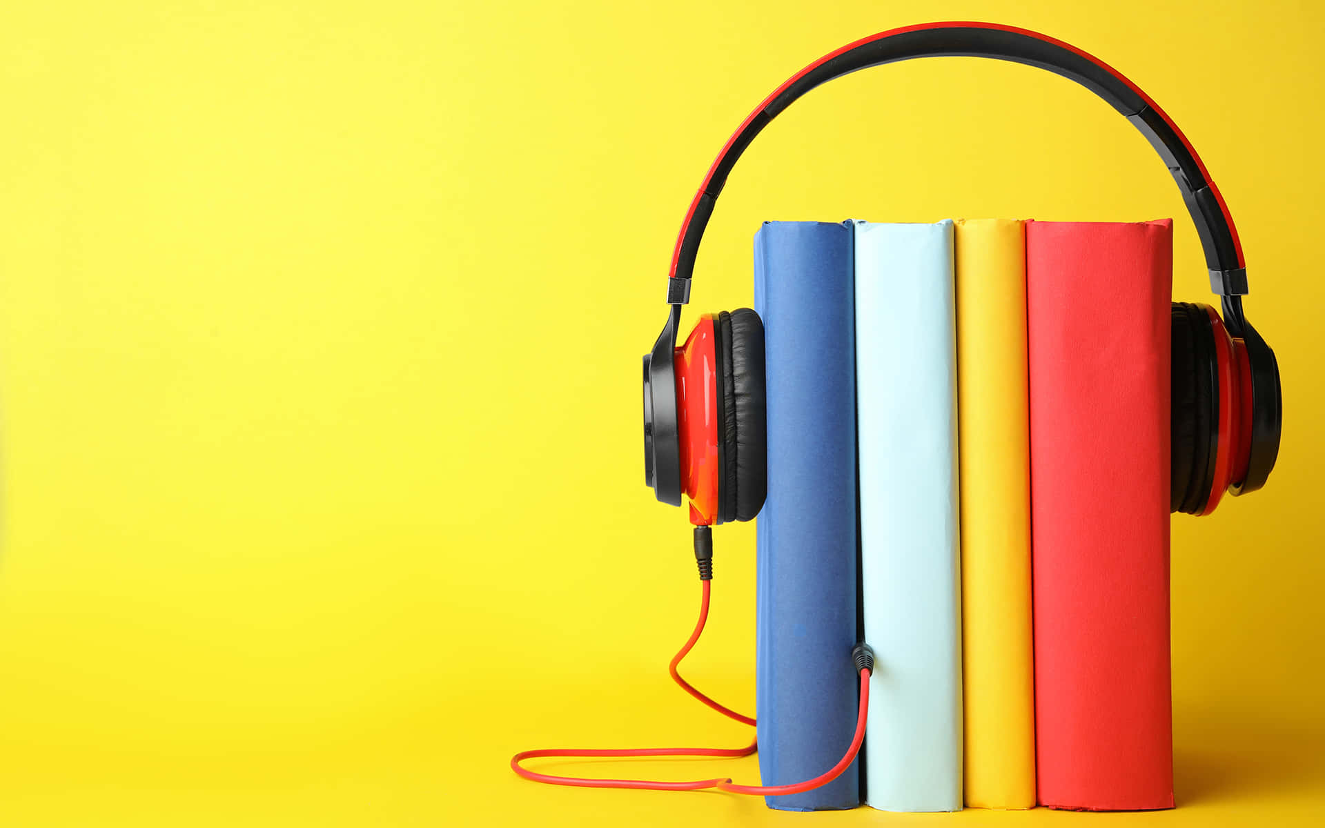 Podcast 桌布 壁紙 — 紅色耳機放在四本色彩繽紛的書上，背景為亮黃色。