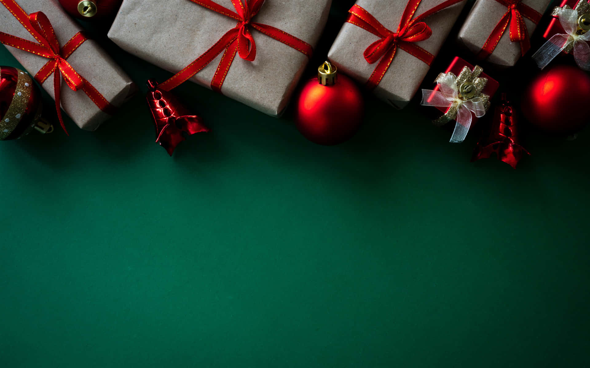 High Resolution Christmas 桌布 壁紙 — 紅色蝴蝶結和裝飾品環繞著綠色表面，包裝好的禮物排列成節日假期構圖。