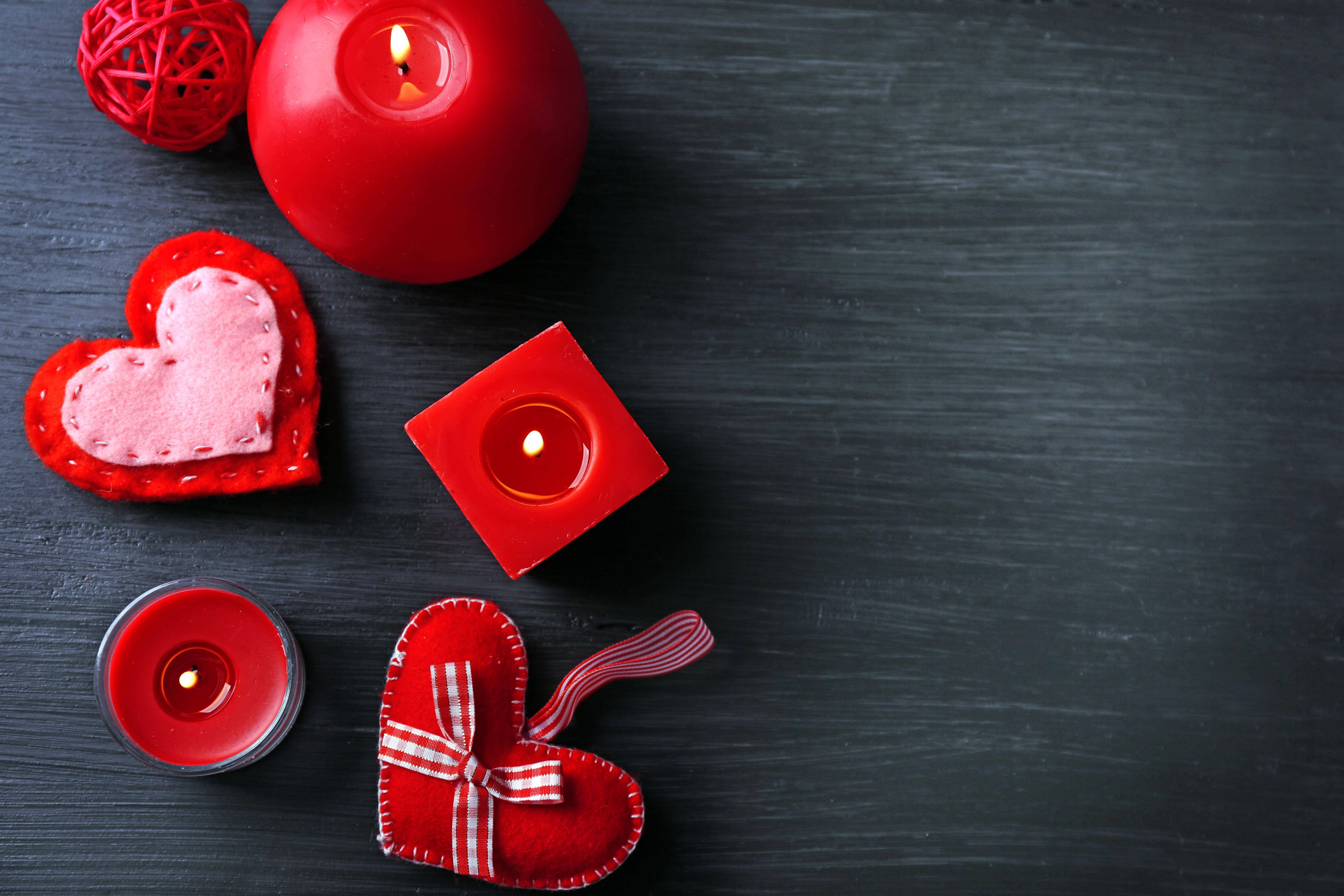 Valentines 桌布 壁紙 — 紅色蠟燭和氈製心形在深色木質表面上溫暖地發光，營造出舒適浪漫的氛圍。