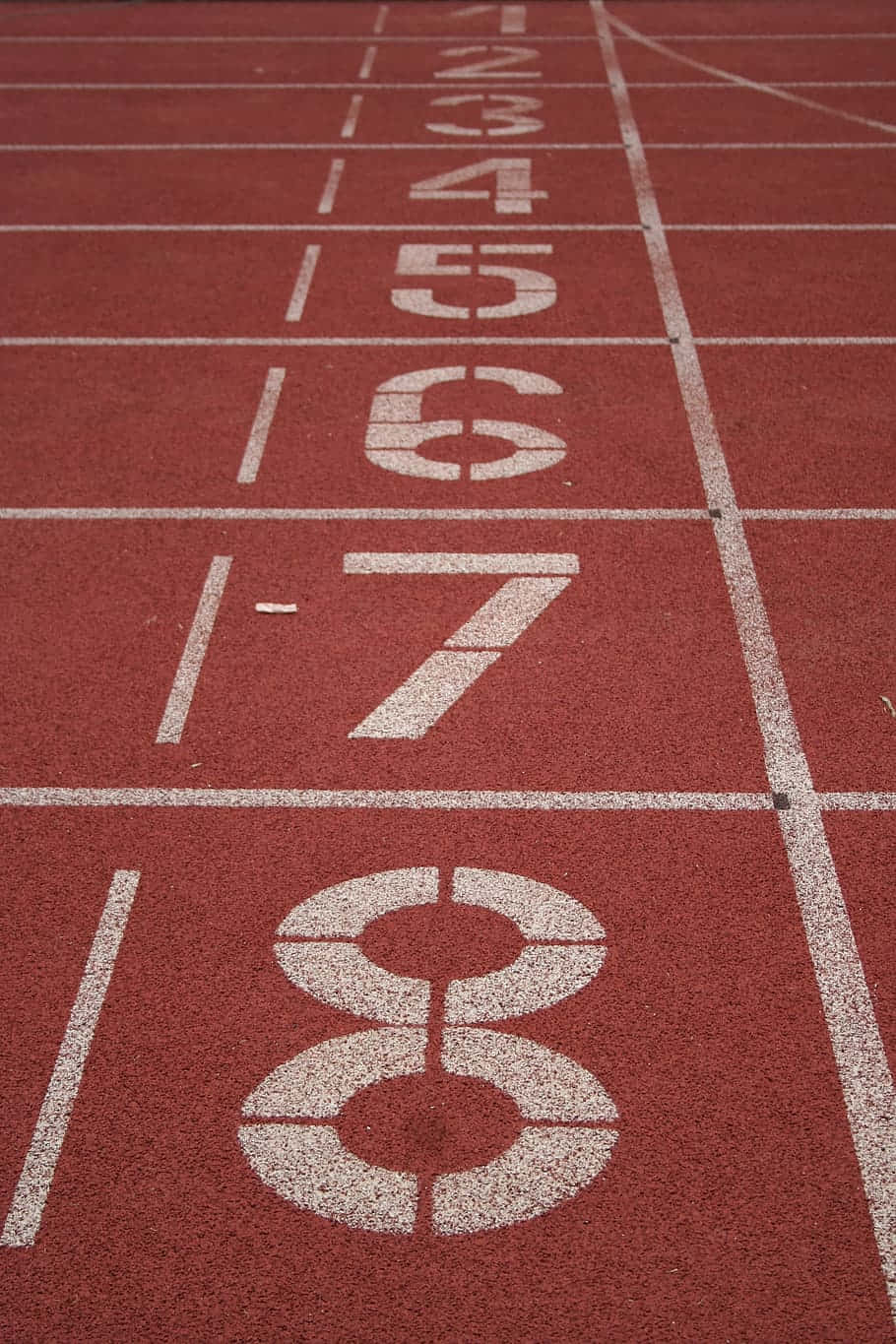 track 桌布 壁紙 — 紅色跑道近景，帶有白色編號的起跑線，專為短跑運動員設計。