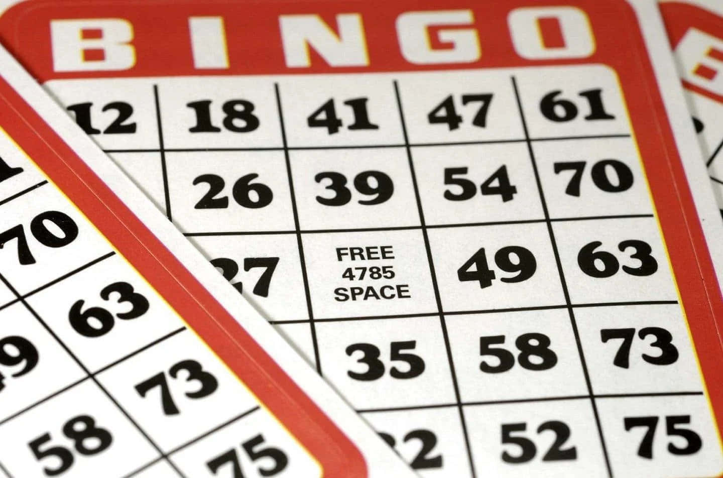 Bingo 桌布 壁紙 — 紅色邊框的賓果卡重疊的特寫，粗體黑色數字和中央的自由空間。