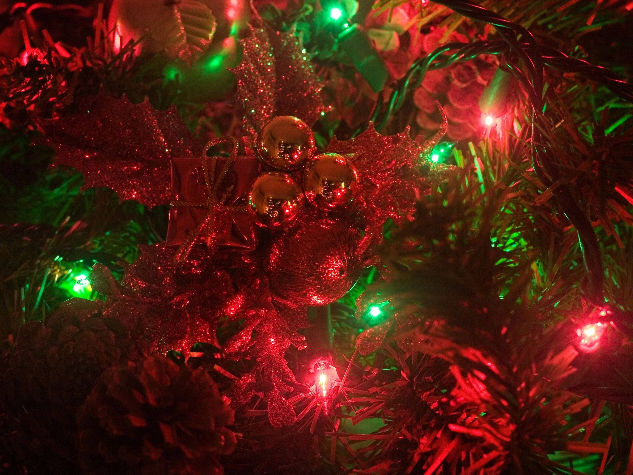 Wreath 桌布 壁紙 — 紅色閃爍冬青和金色裝飾品在紅綠聖誕燈光下閃耀的特寫。