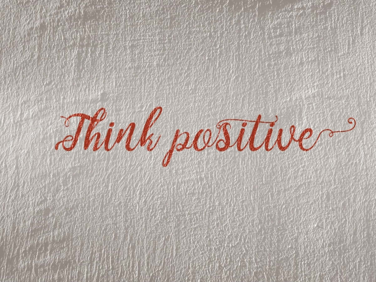 正向 桌布 壁紙 — 紅色閃粉草書文字「Think positive」寫在帶紋理的銀色牆上。
