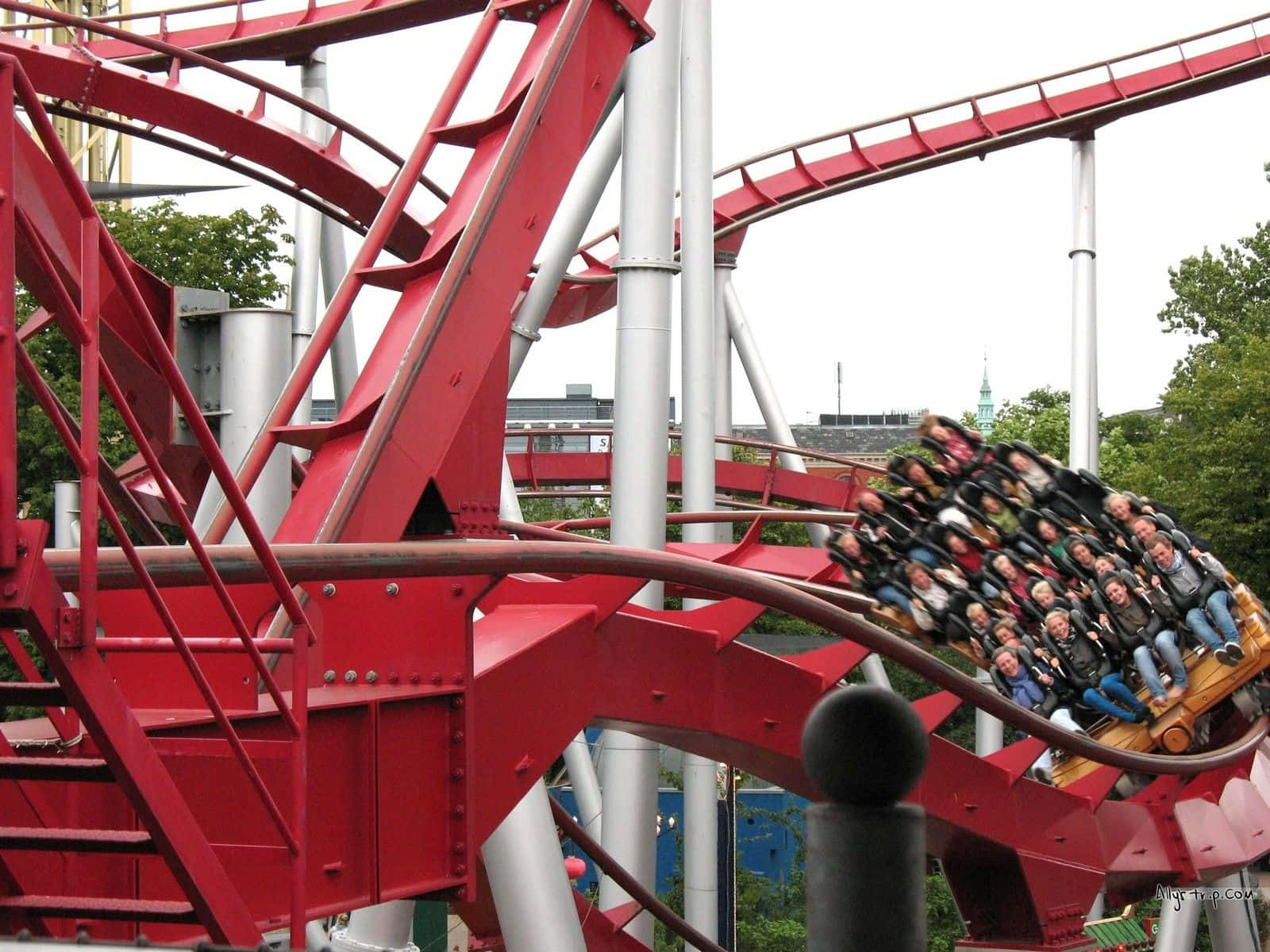 Roller Coaster 桌布 壁紙 — 紅色雲霄飛車在遊樂園中蜿蜒曲折，乘客在驚險的迴圈中興奮尖叫。