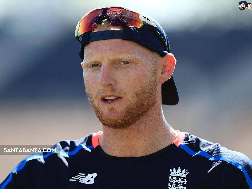 Ben Stokes 桌布 壁紙 — 紅髮板球球員戴著帽子和隊服在戶外明亮日光下的特寫。