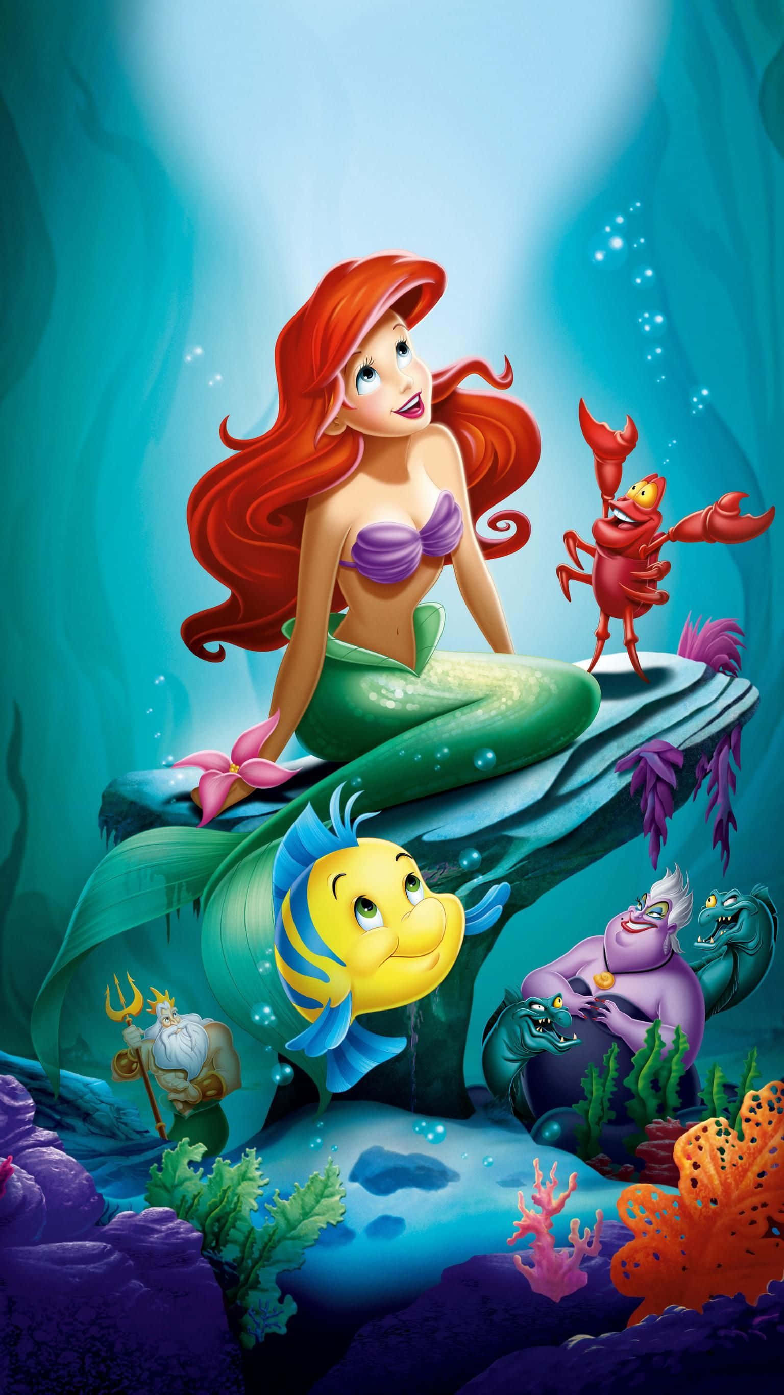 little mermaid 桌布 壁紙 — 紅髮美人魚艾莉兒坐在水中的岩石上微笑，她的朋友塞巴斯丁和小比目魚在她身邊。