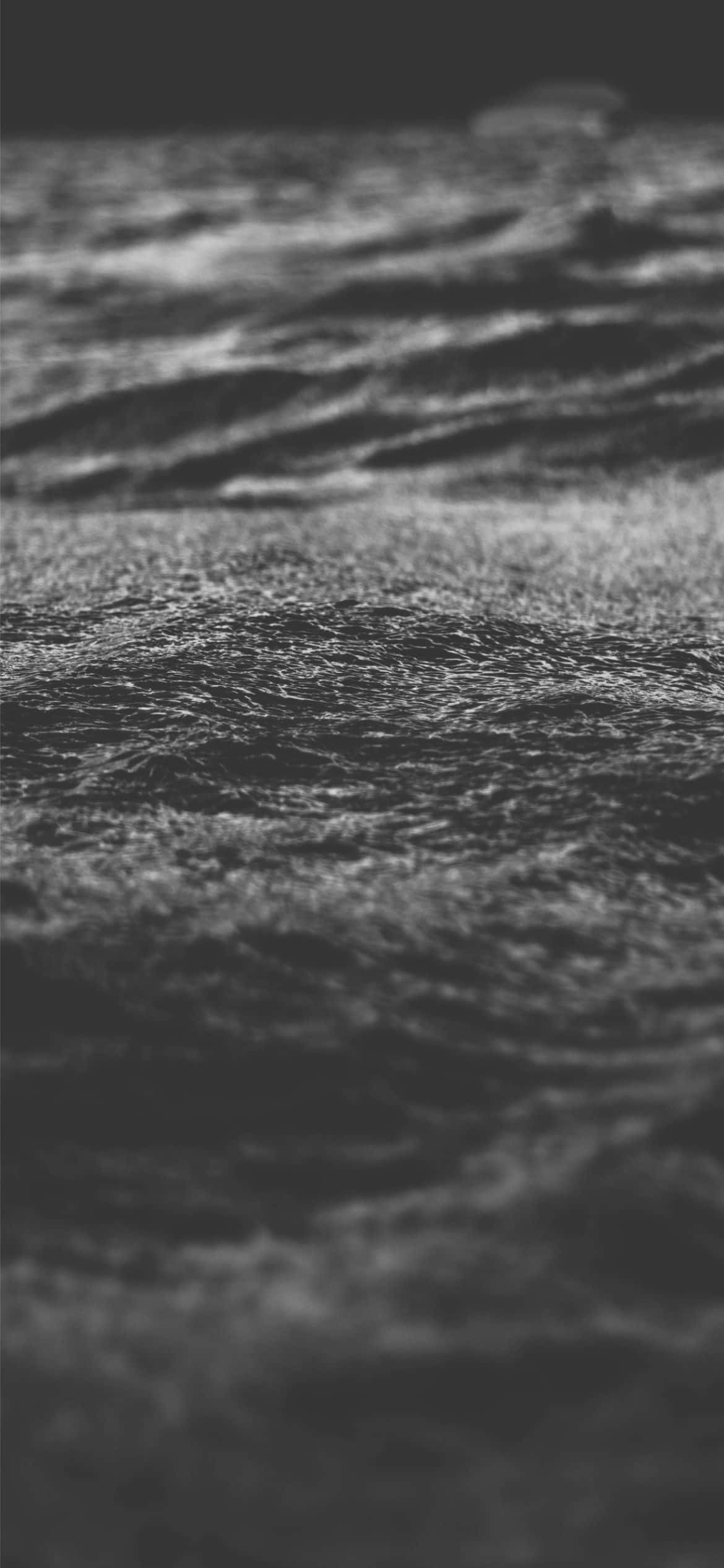 Black Sad 桌布 壁紙 — 紋理海浪的單色特寫，柔和光線在漣漪水面反射。