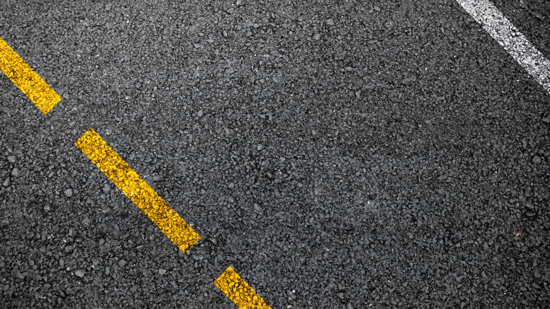 Textured 桌布 壁紙 — 紋理瀝青道路的特寫，帶有粗體的黃色和白色油漆線標記車道。
