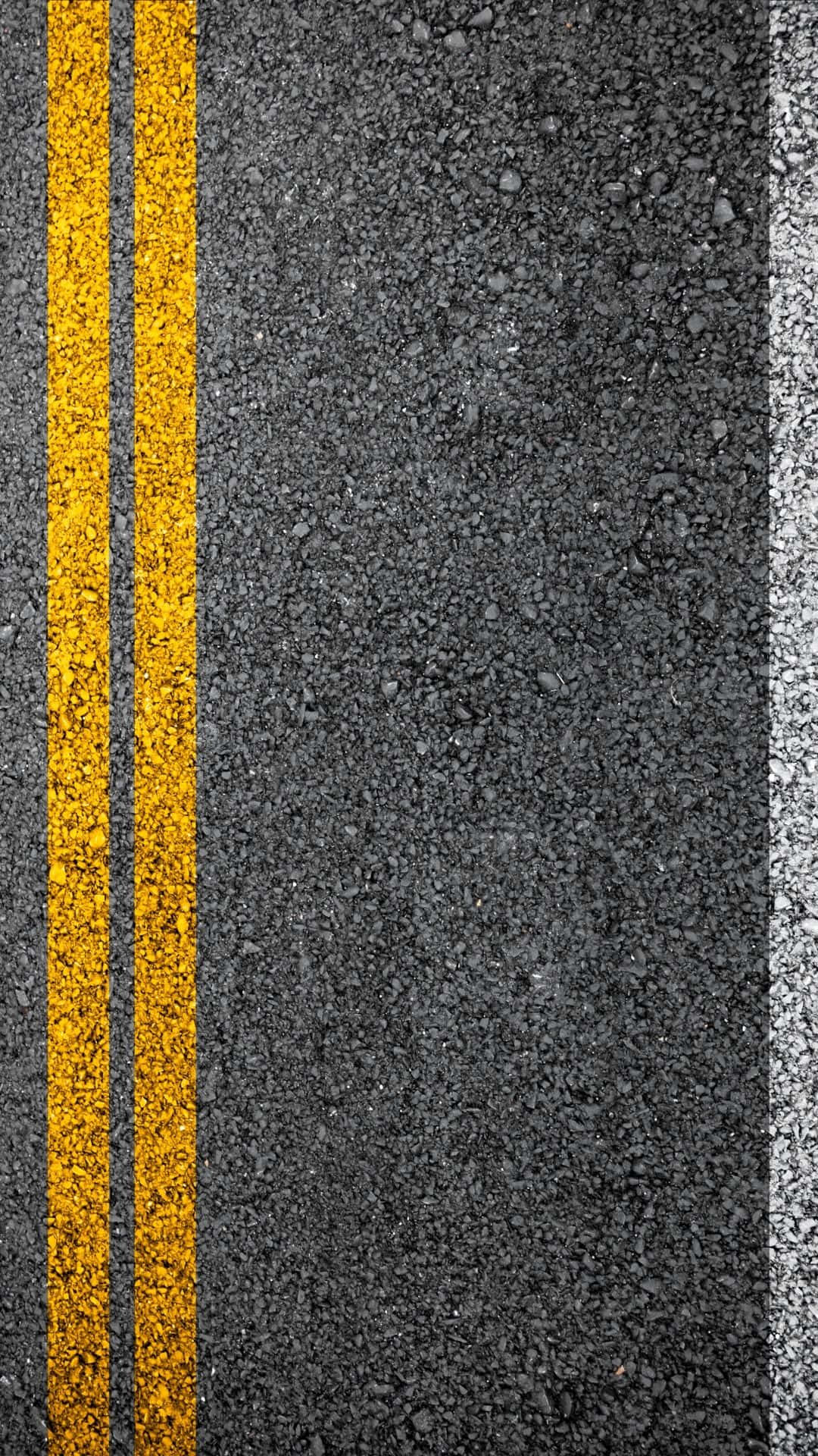 Textured 桌布 壁紙 — 紋理瀝青道路的特寫，帶有粗黃色雙線和白色邊緣標記。