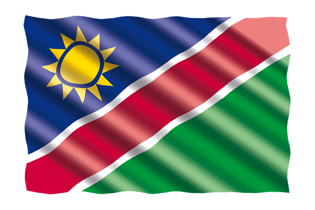 Namibia 桌布 壁紙 — 納米比亞國旗動態飄揚，藍色旗面、黃色太陽，以及白色邊框的紅綠斜紋。