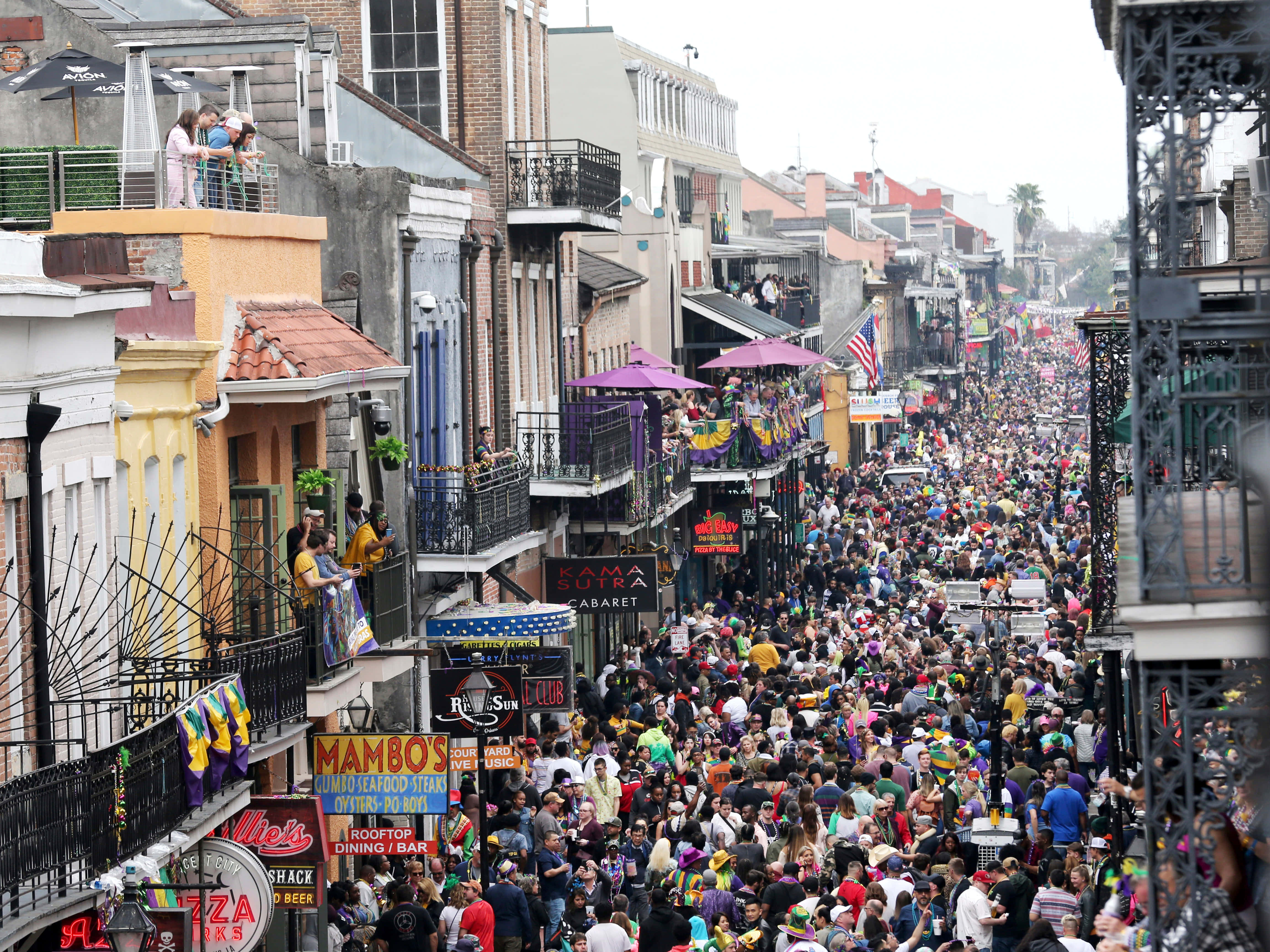 Mardi Gras 桌布 壁紙 — 紐奧良一條熙熙攘攘的街道，擠滿了在色彩繽紛的陽台和節日旗幟下慶祝的人群。