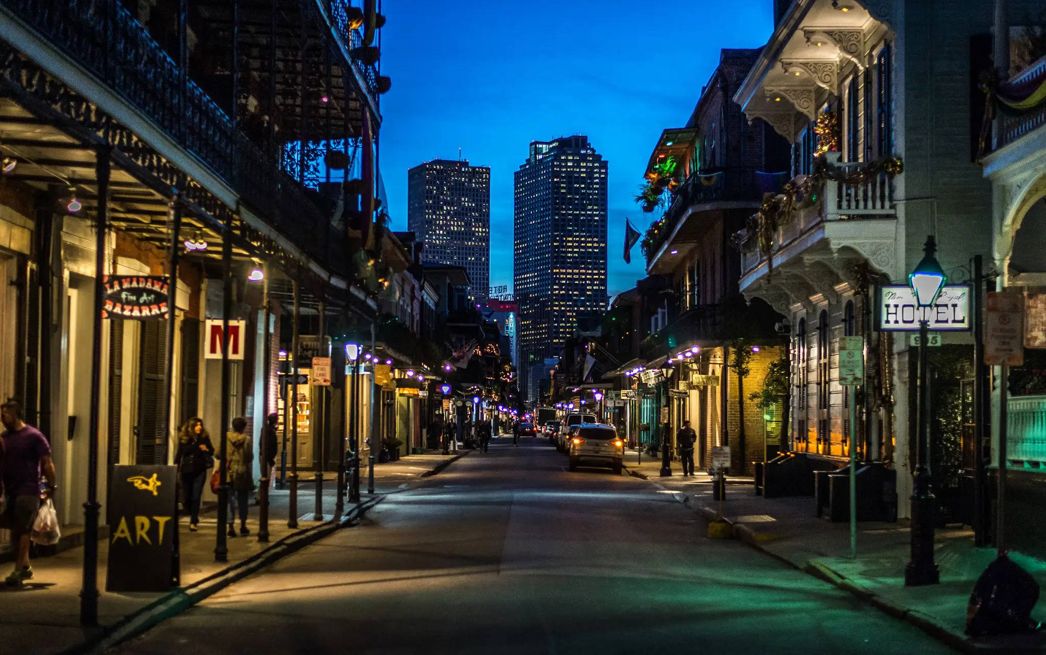 New Orleans 桌布 壁紙 — 紐奧良的黃昏街道，擁有歷史建築、閃爍燈光和一輛行駛在路上的汽車。