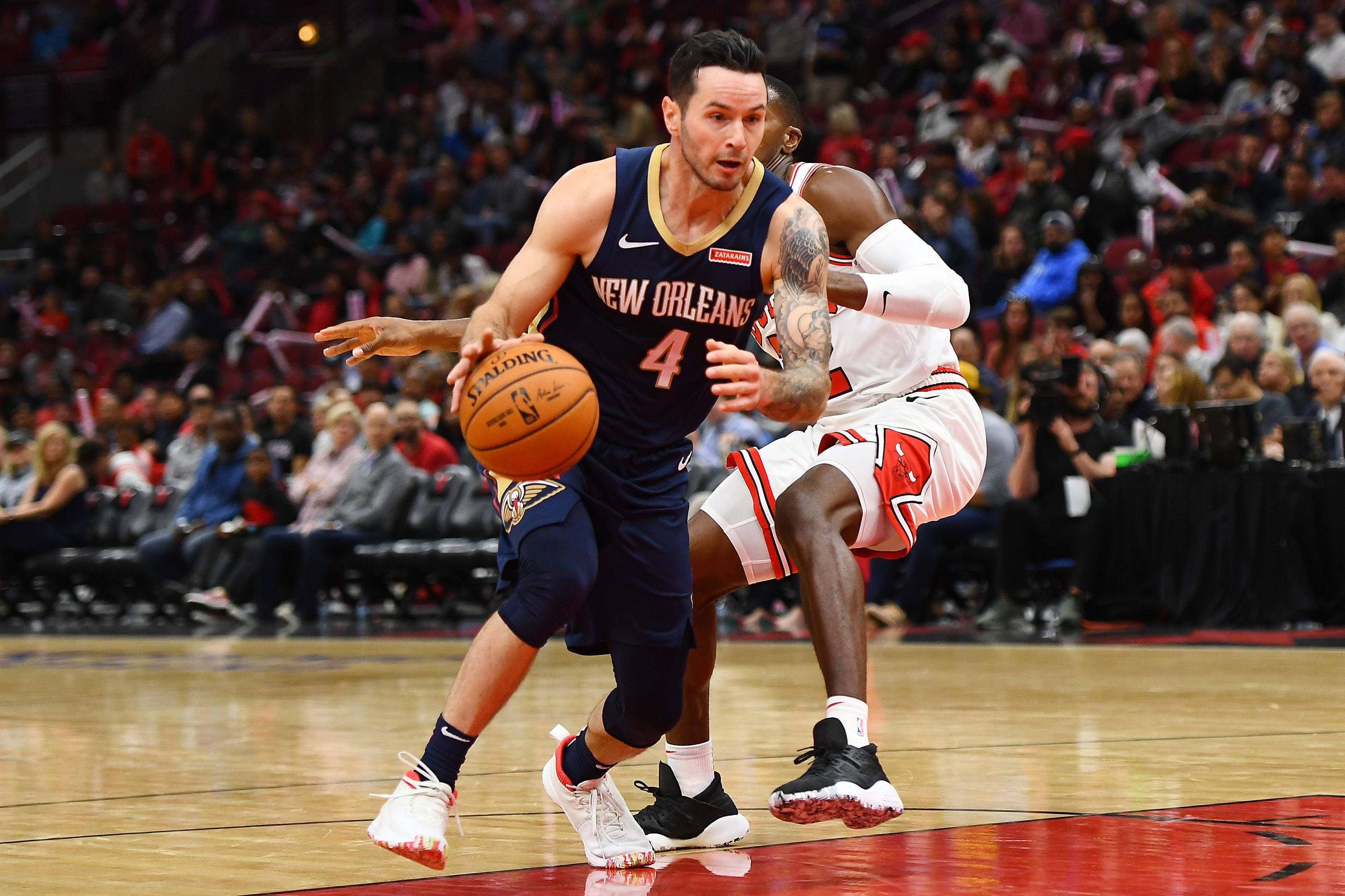 Jj Redick 桌布 壁紙 — 紐奧良鵜鶘隊球員在擠滿人的籃球場上運球，同時被對手緊密防守。