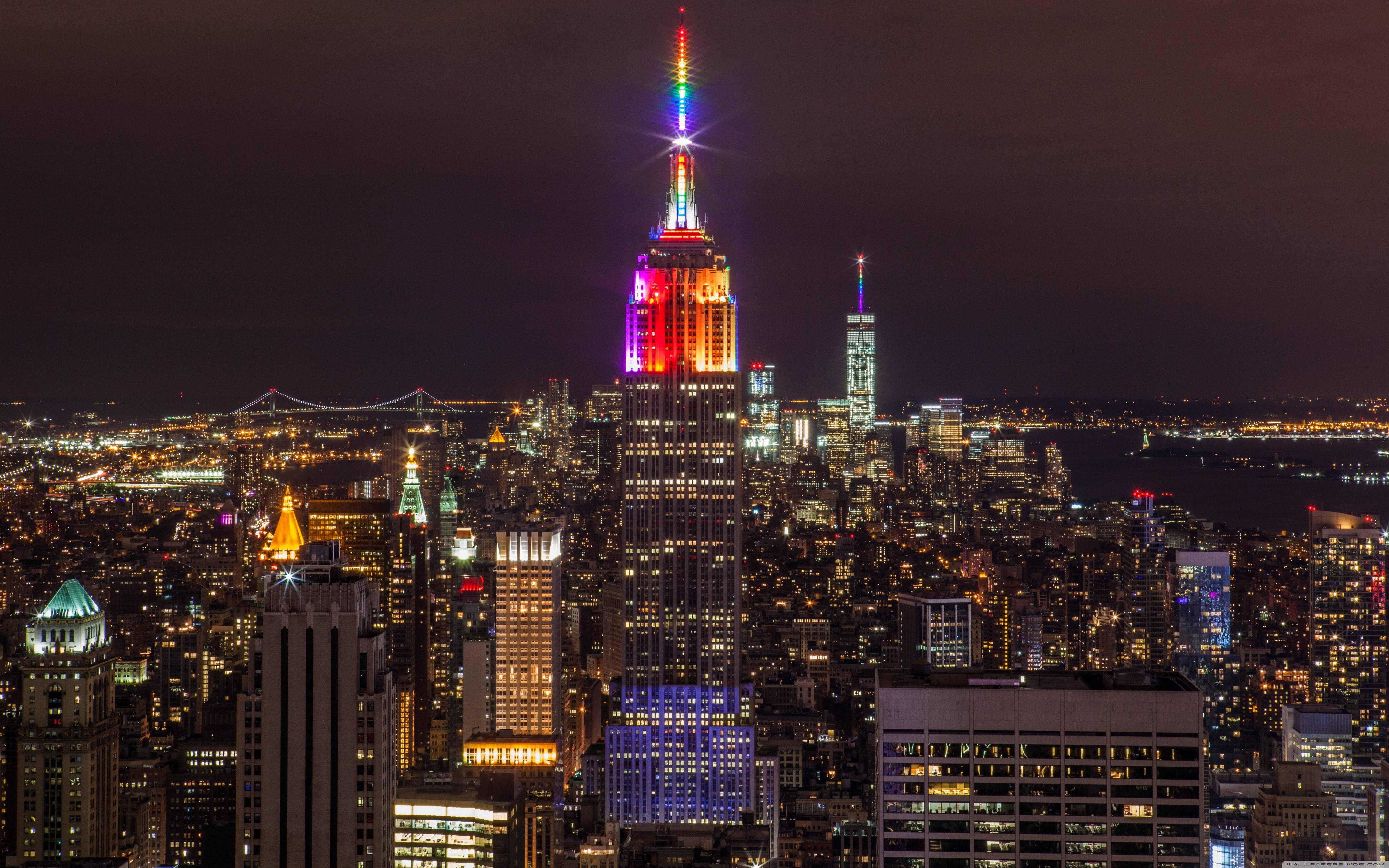 New York 桌布 壁紙 — 紐約令人目眩的夜景，帝國大廈在黑暗的天空中閃爍著彩虹燈光。