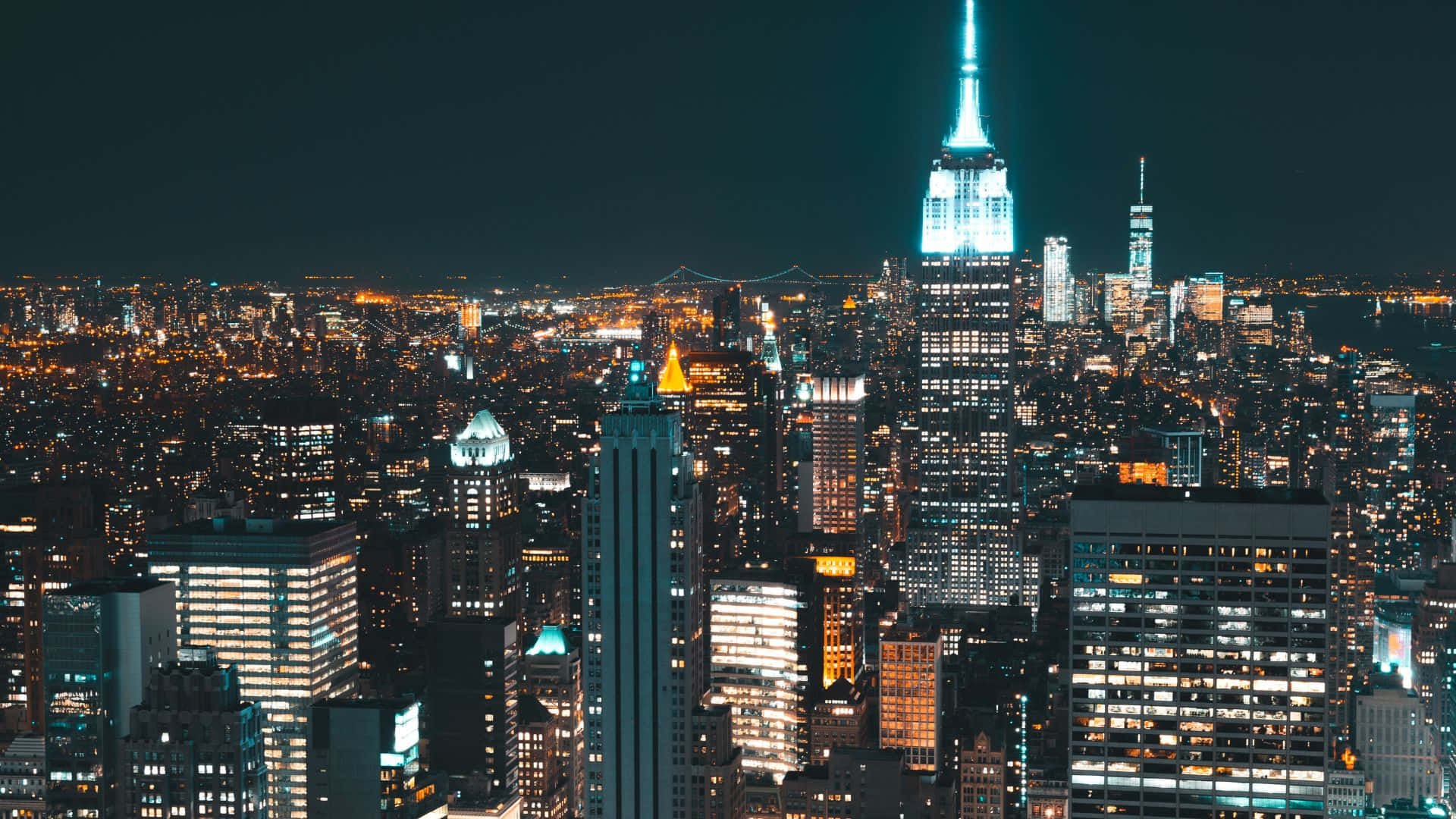 美國 桌布 壁紙 — 紐約令人目眩的夜景，帝國大廈閃爍著藍光，無數窗戶在漆黑的天空中亮起。