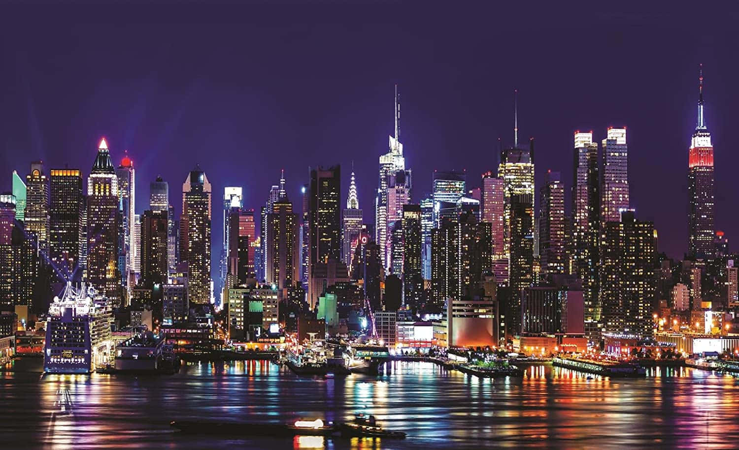 紐約市 桌布 壁紙 — 紐約令人目眩的夜景，摩天大樓在深紫色的天空下閃耀，燈光倒映在下方漆黑的水面上。