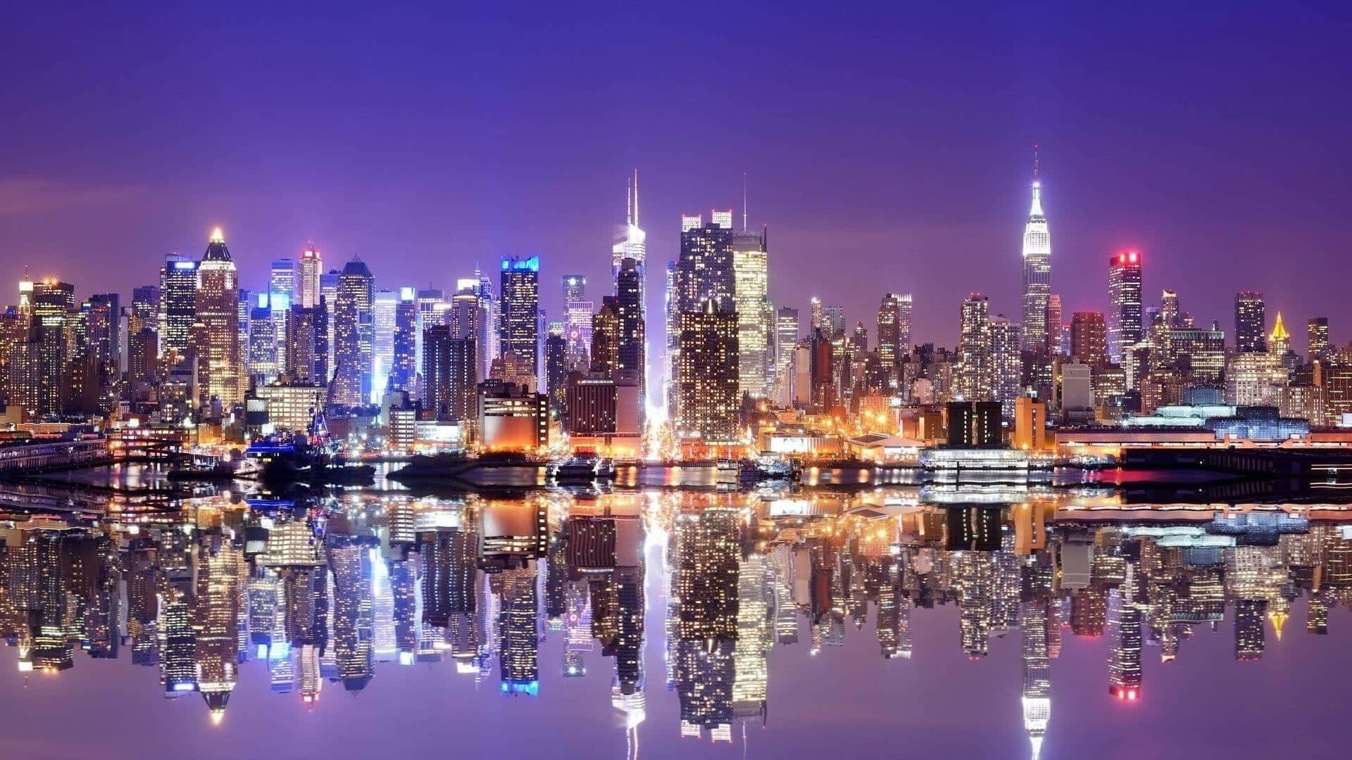 Panoramic Desktop 桌布 壁紙 — 紐約令人目眩的夜景，摩天大樓在紫色天空下閃耀，完美倒映在平靜的水面上。