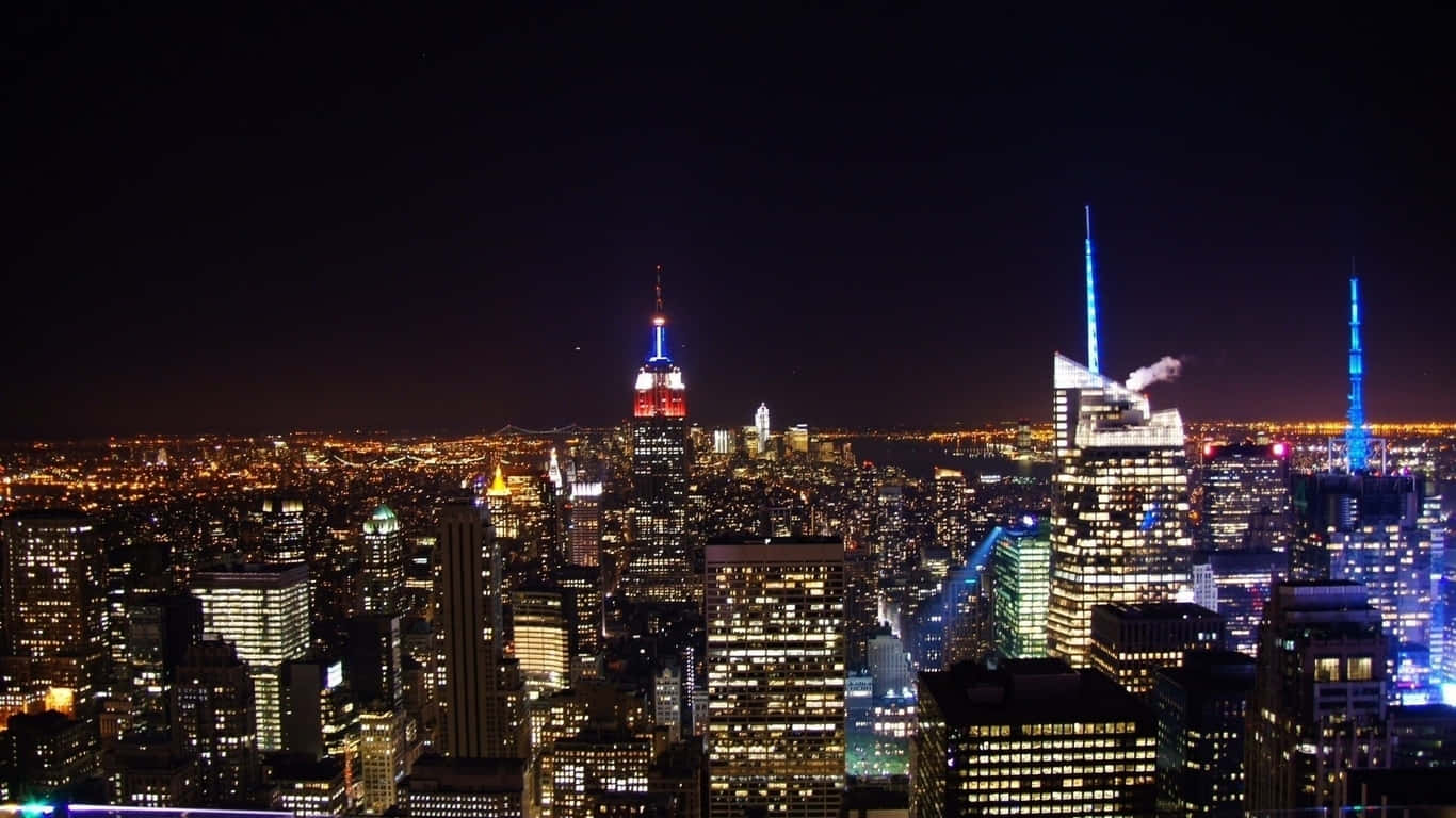 1366x768 Empire State Building 桌布 壁紙 — 紐約令人目眩的夜景，摩天大樓燈火通明，窗戶閃爍，襯托著漆黑的天空。
