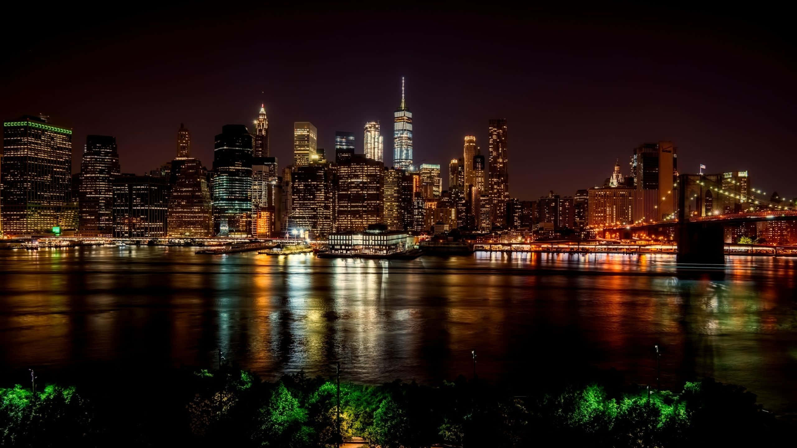 紐約市 桌布 壁紙 — 紐約令人目眩的夜景，照亮了的摩天大樓和發光的橋樑倒映在漆黑的水面上。