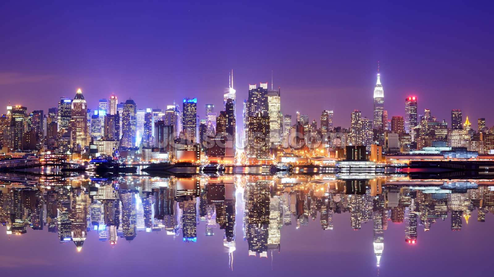 New York 桌布 壁紙 — 紐約令人驚嘆的夜景，摩天大樓在深紫色天空下閃耀，完美倒映在下方平靜的水面上。