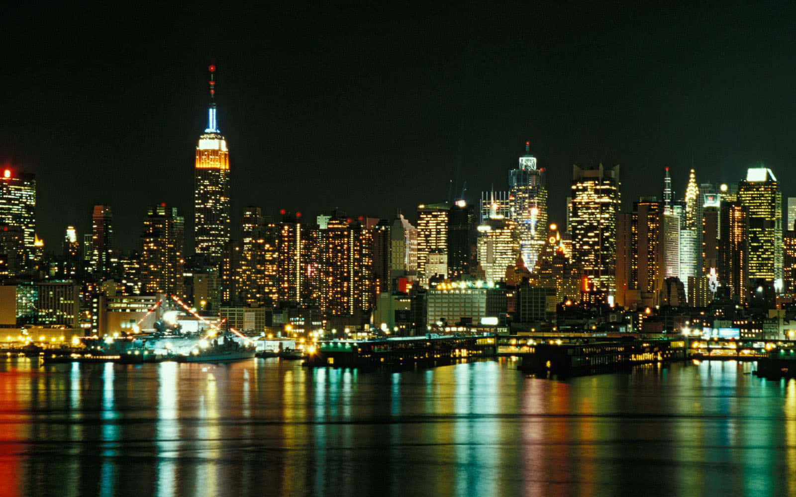 Nyc 桌布 壁紙 — 紐約令人驚嘆的夜景，燈火通明的摩天大樓倒映在黑暗的水面上。