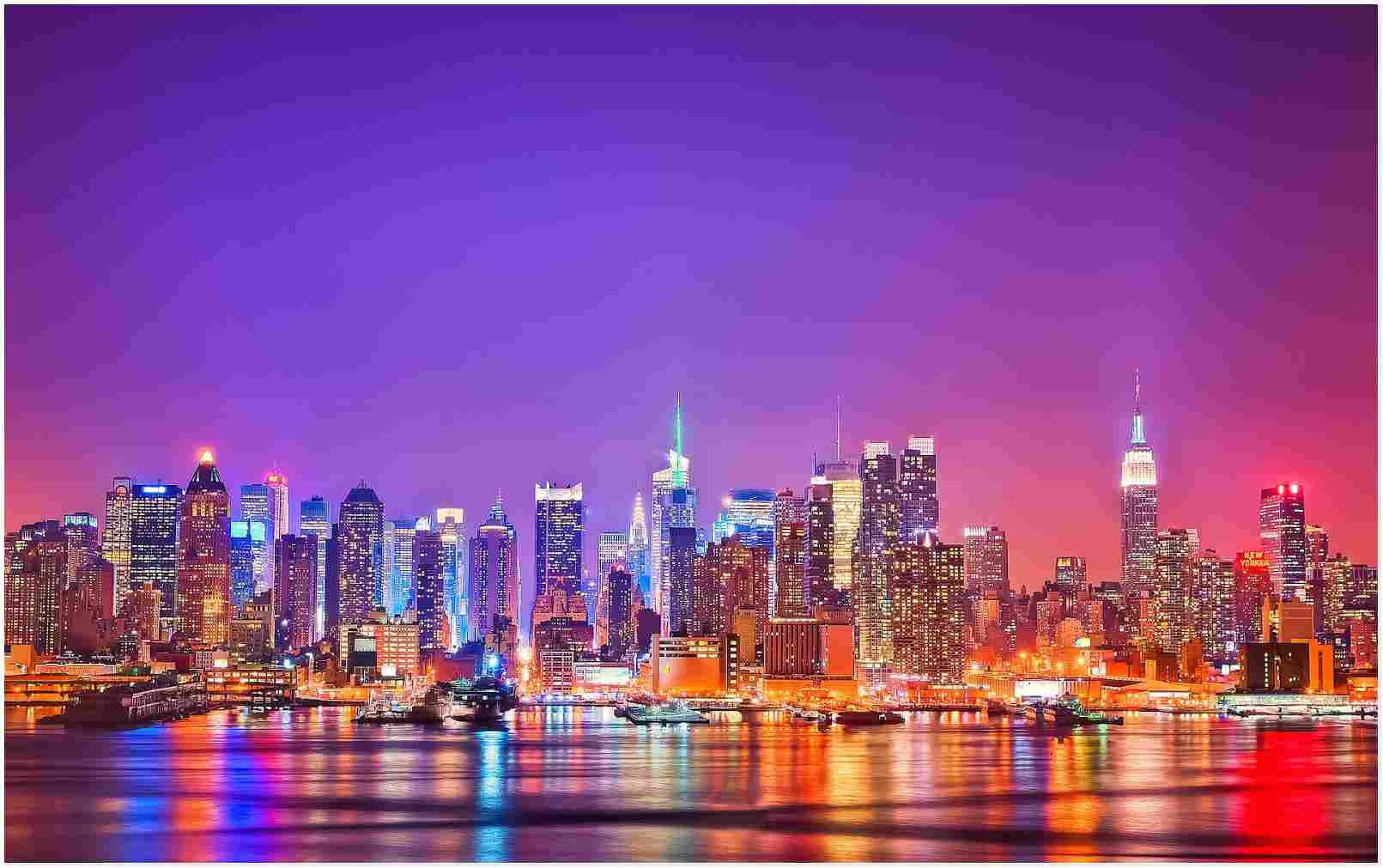 Nyc Aesthetic 桌布 壁紙 — 紐約充滿活力的夜景，摩天大樓在紫色和粉紅色的天空下閃閃發光，倒映在水中。