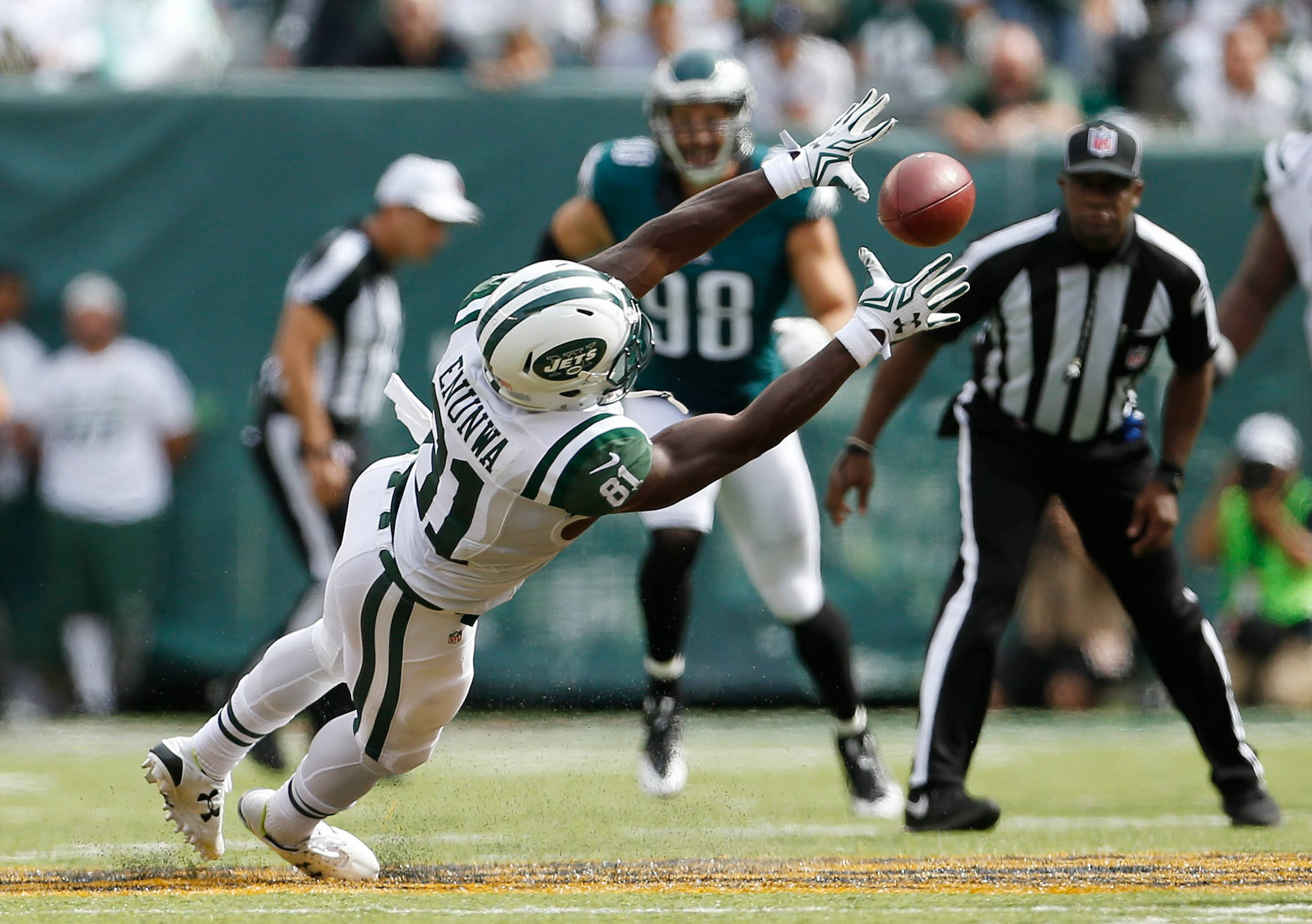 Ny Jets 桌布 壁紙 — 紐約噴射機隊的外接手向端區飛撲，伸手去接橄欖球，裁判和防守球員專注地看著。