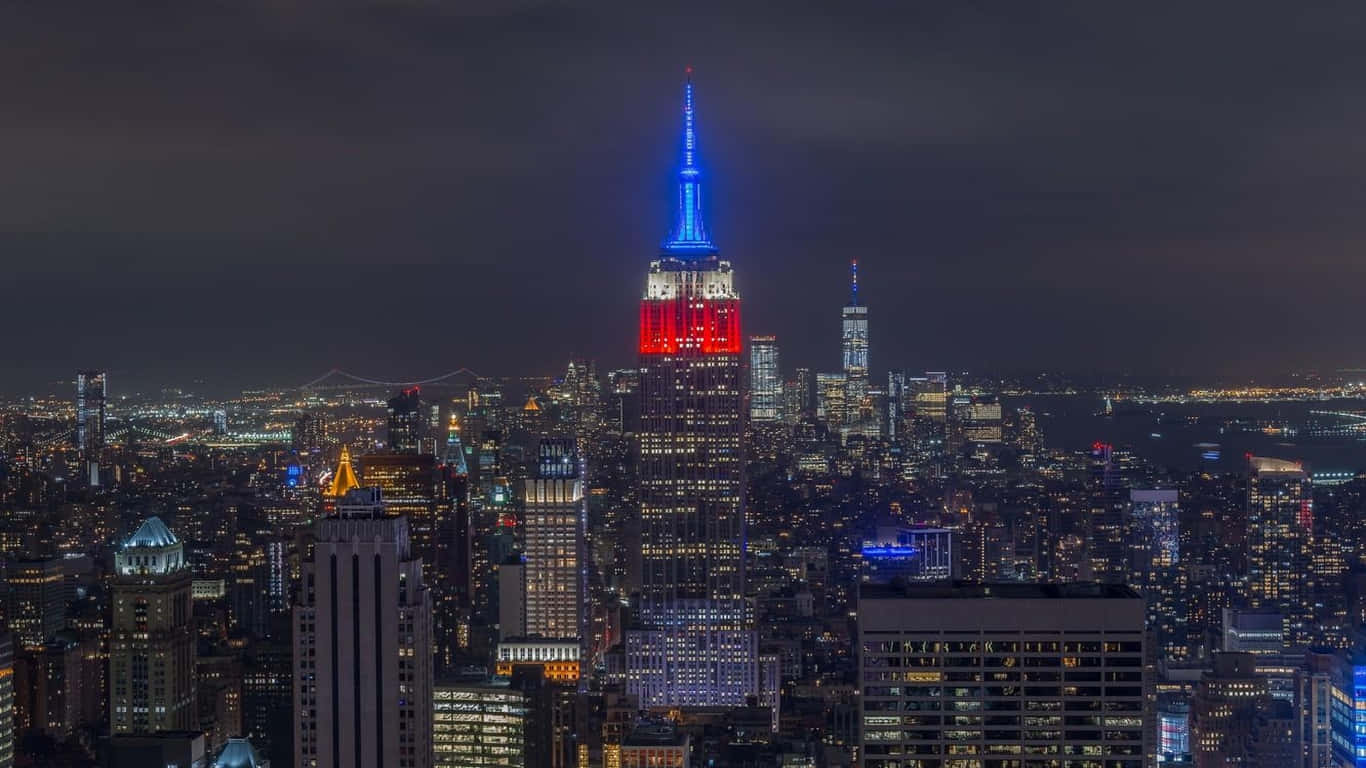 1366x768 Empire State Building 桌布 壁紙 — 紐約夜景，帝國大廈在黑暗的天空下以紅藍燈光點亮。