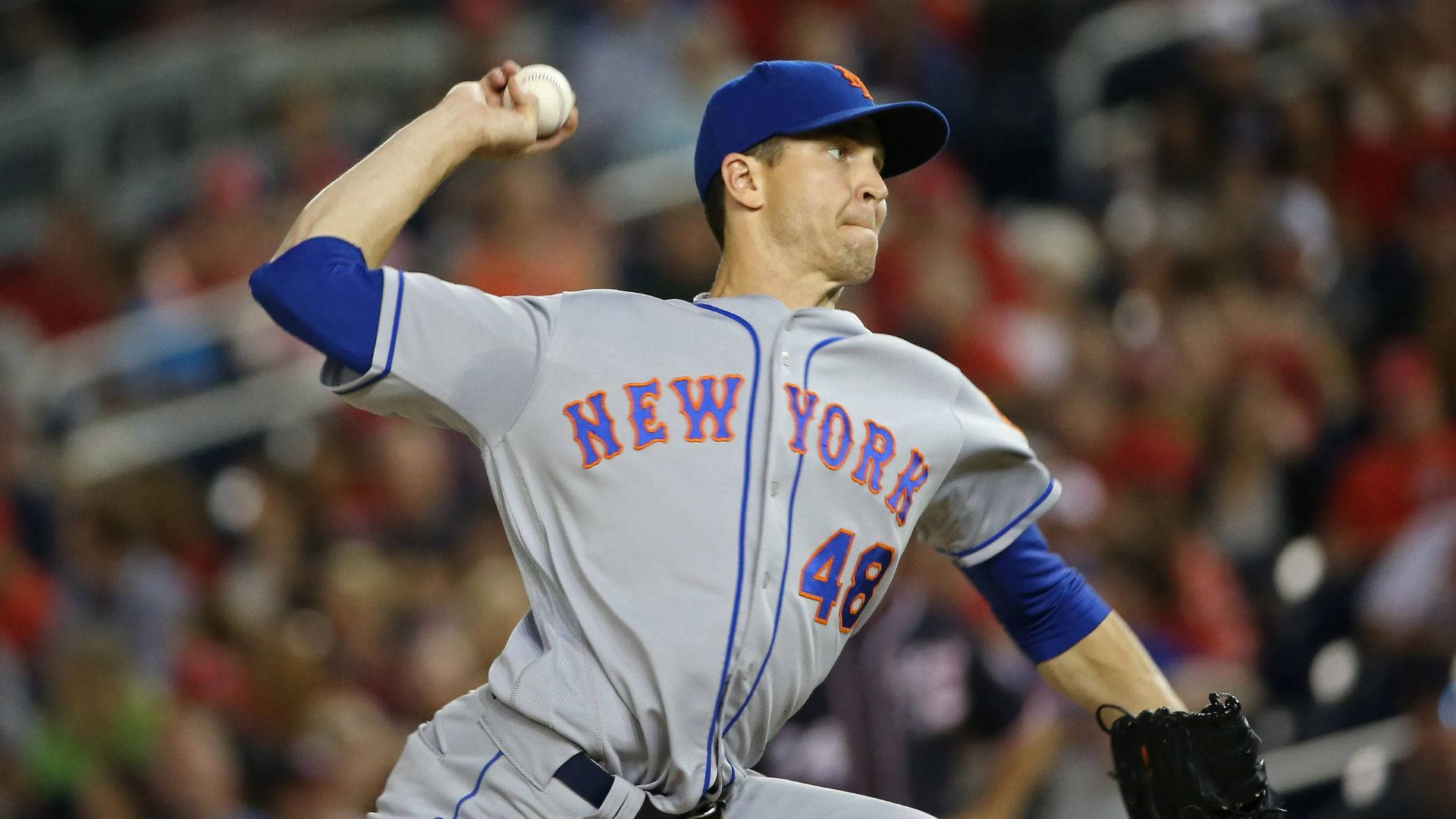 Degrom 桌布 壁紙 — 紐約大都會棒球投手在夜間比賽中投球，背景是模糊的體育場人群。