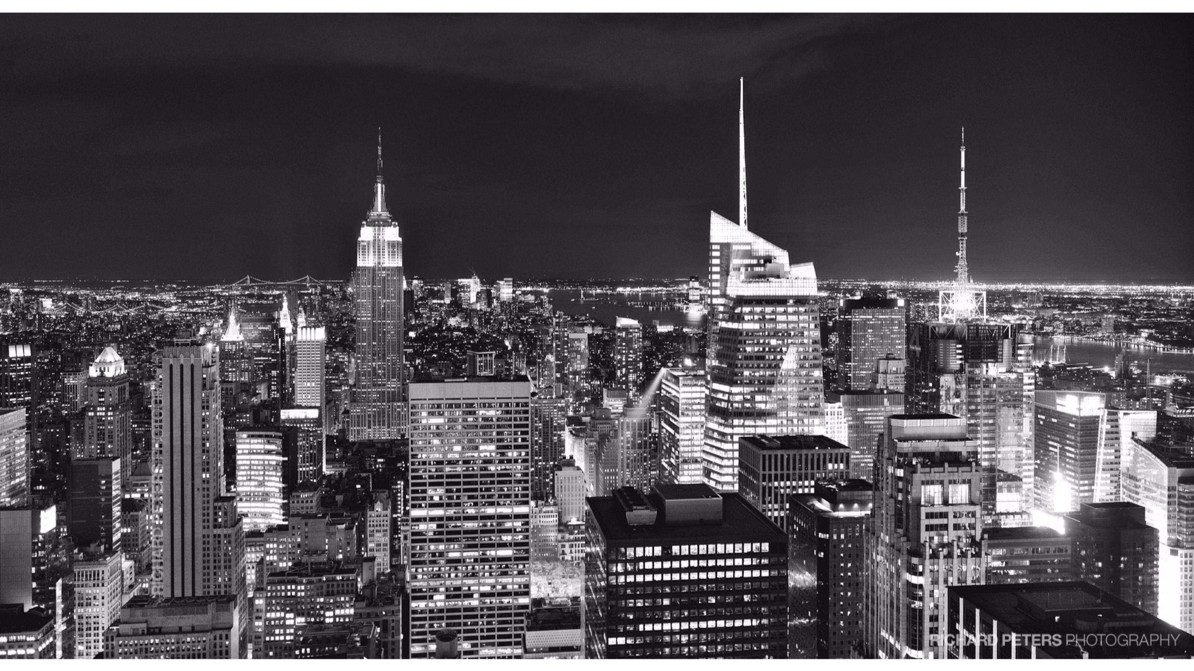New York 桌布 壁紙 — 紐約市夜晚的醒目黑白航拍圖，展現了燈火通明的摩天大樓和黑暗的天空。