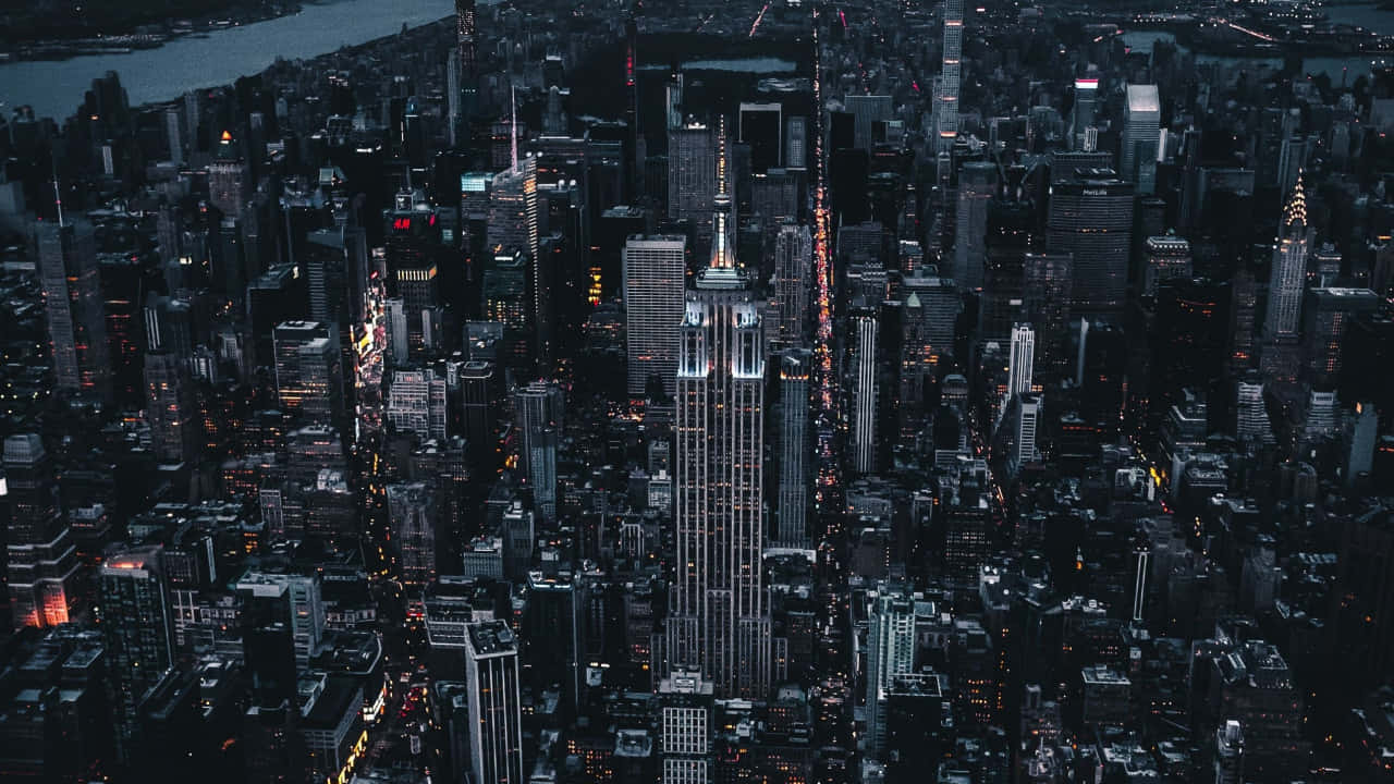 720p Ny City 桌布 壁紙 — 紐約市夜景鳥瞰圖，帝國大廈在黑暗的摩天大樓和河燈中閃耀。