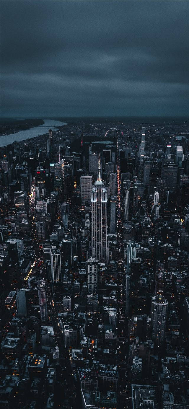 iPhone 桌布 壁紙 — 紐約市夜景鳥瞰圖，帝國大廈在黑暗多雲的天空中亮起。