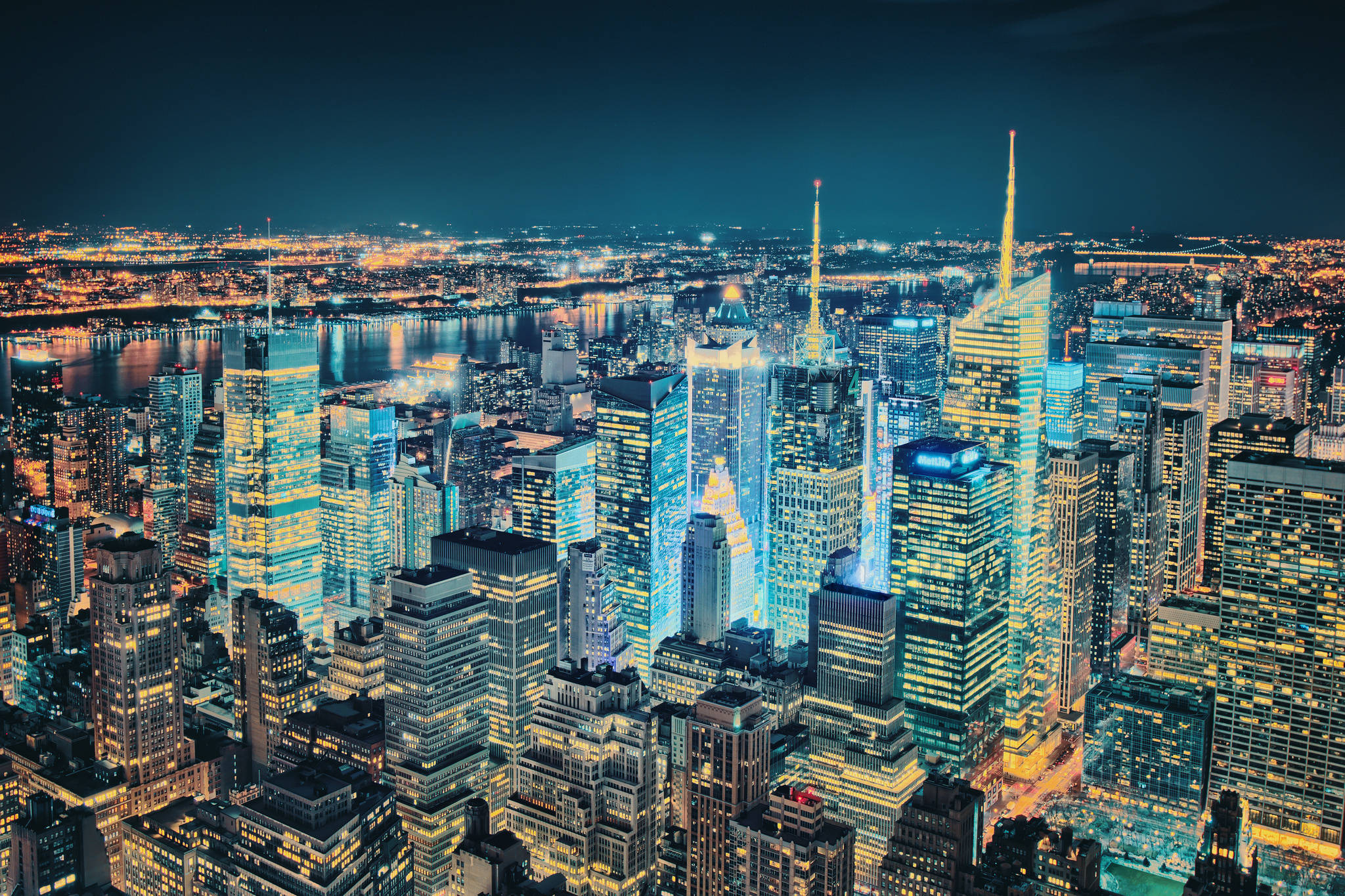 Nyc 桌布 壁紙 — 紐約市夜景鳥瞰圖，摩天大樓在黑暗天空下閃耀，倒映在水面上。