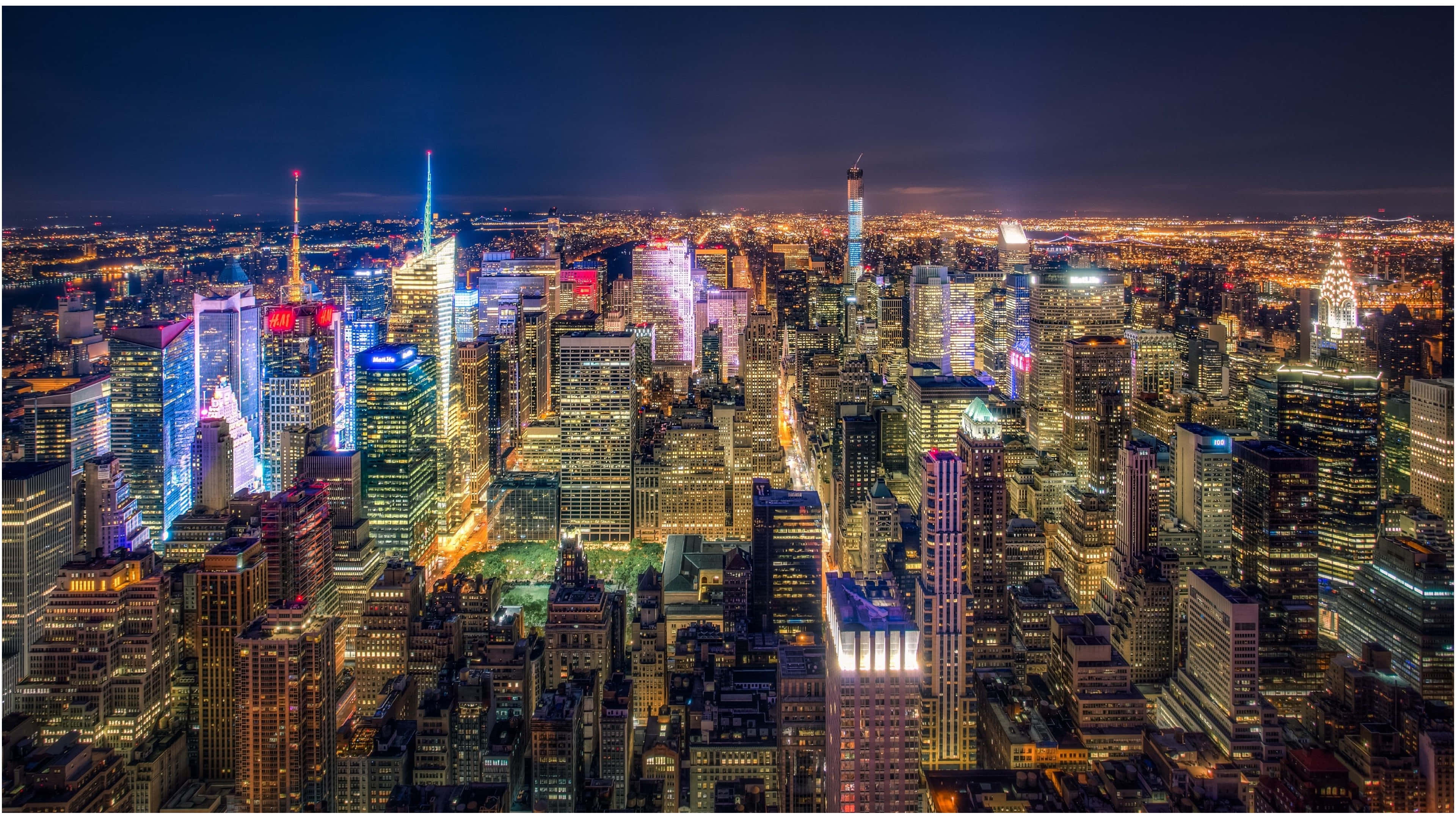 Skyscraper 桌布 壁紙 — 紐約市夜景鳥瞰圖，摩天大樓在黑暗的天空中閃爍著鮮豔的霓虹燈光。