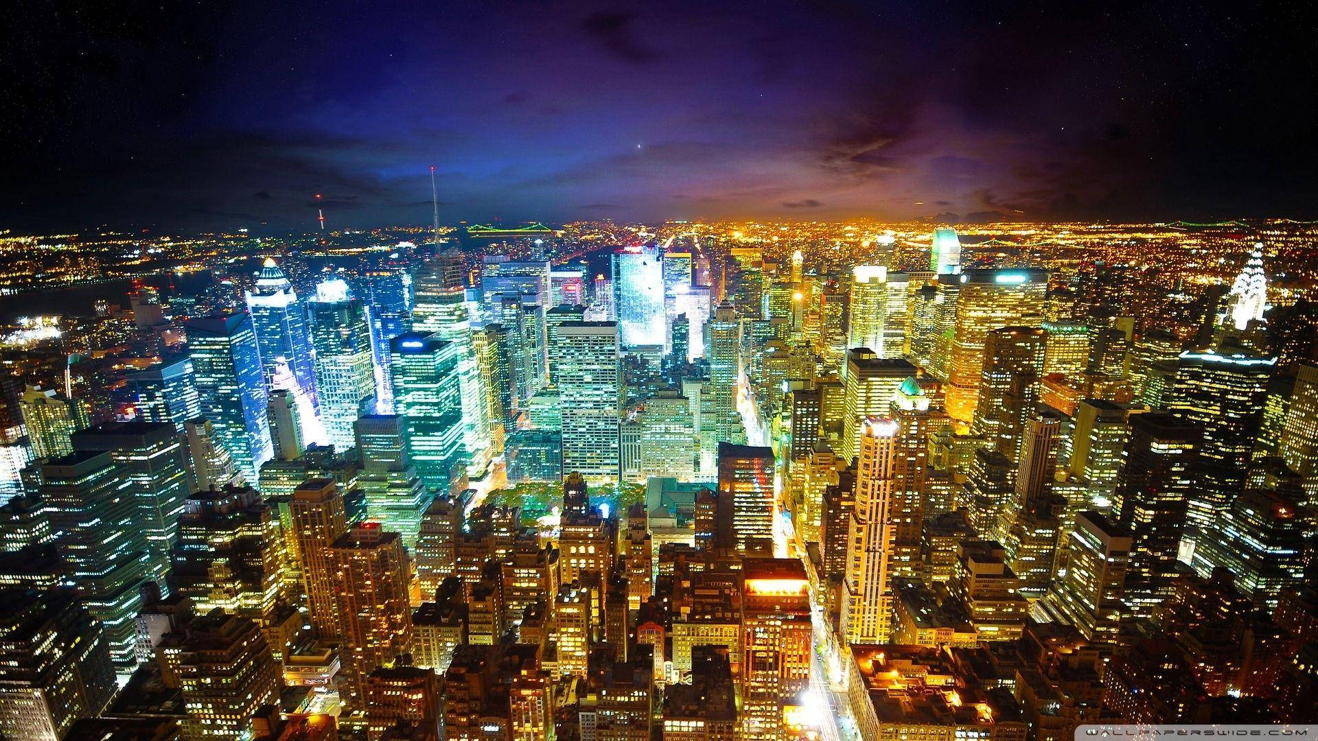New York 桌布 壁紙 — 紐約市夜景鳥瞰圖，深紫色天空下閃爍的摩天大樓。
