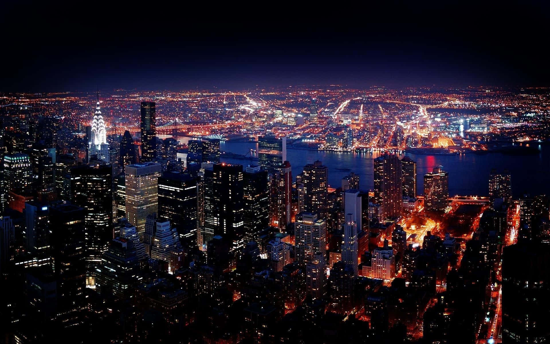 City Night 桌布 壁紙 — 紐約市夜景鳥瞰圖，黑暗水面上有發光的摩天大樓和照明橋樑。