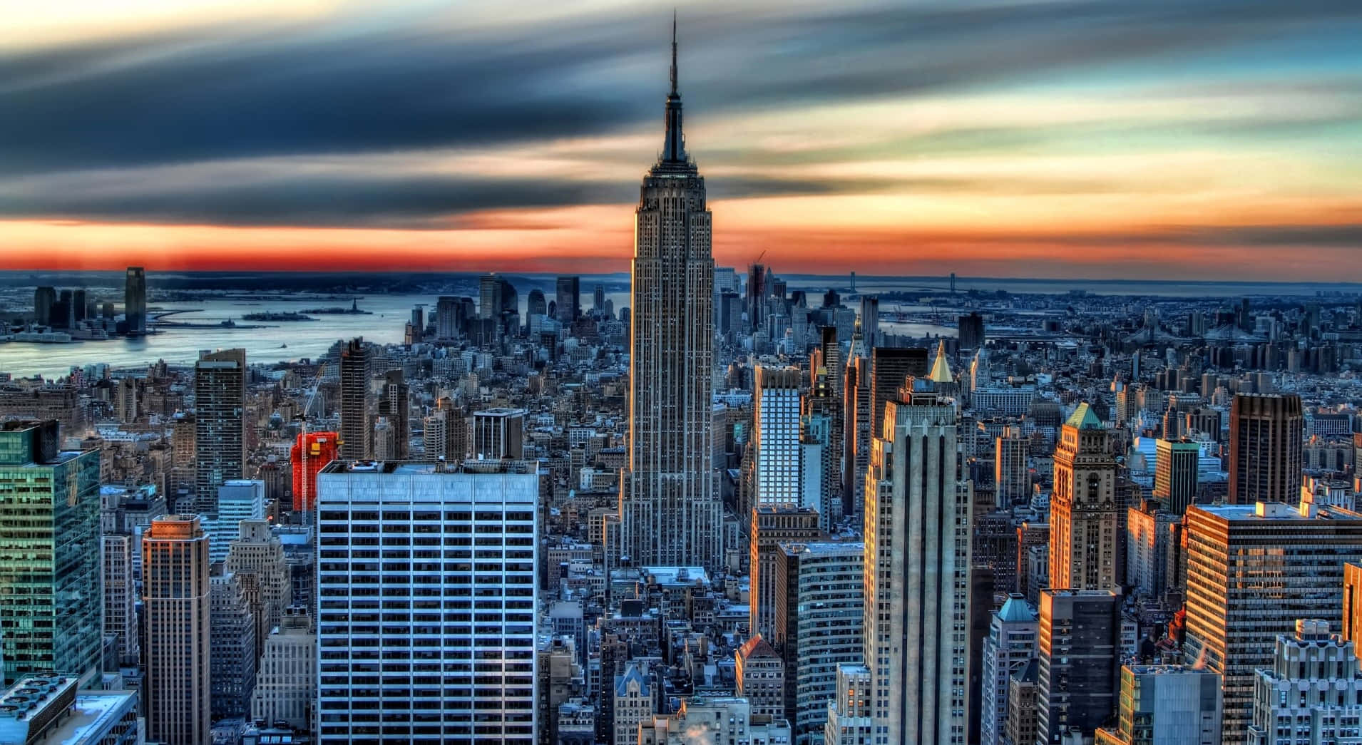 New York 桌布 壁紙 — 紐約市天際線上的壯麗日落，帝國大廈聳立在密集的城市景觀之上。