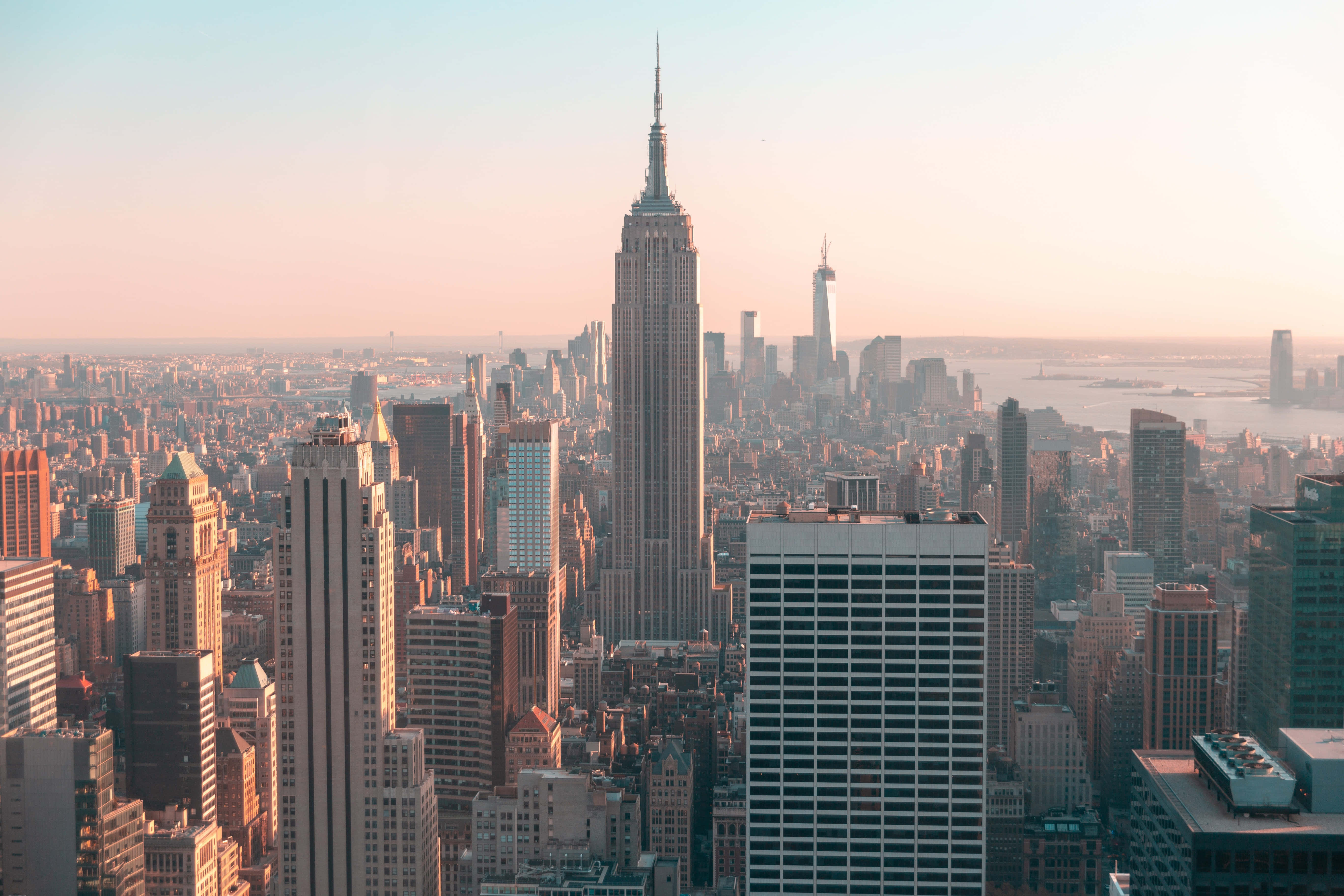 Nyc 桌布 壁紙 — 紐約市天際線在日出時的壯麗航拍景色，金色陽光灑滿帝國大廈及周圍摩天大樓。