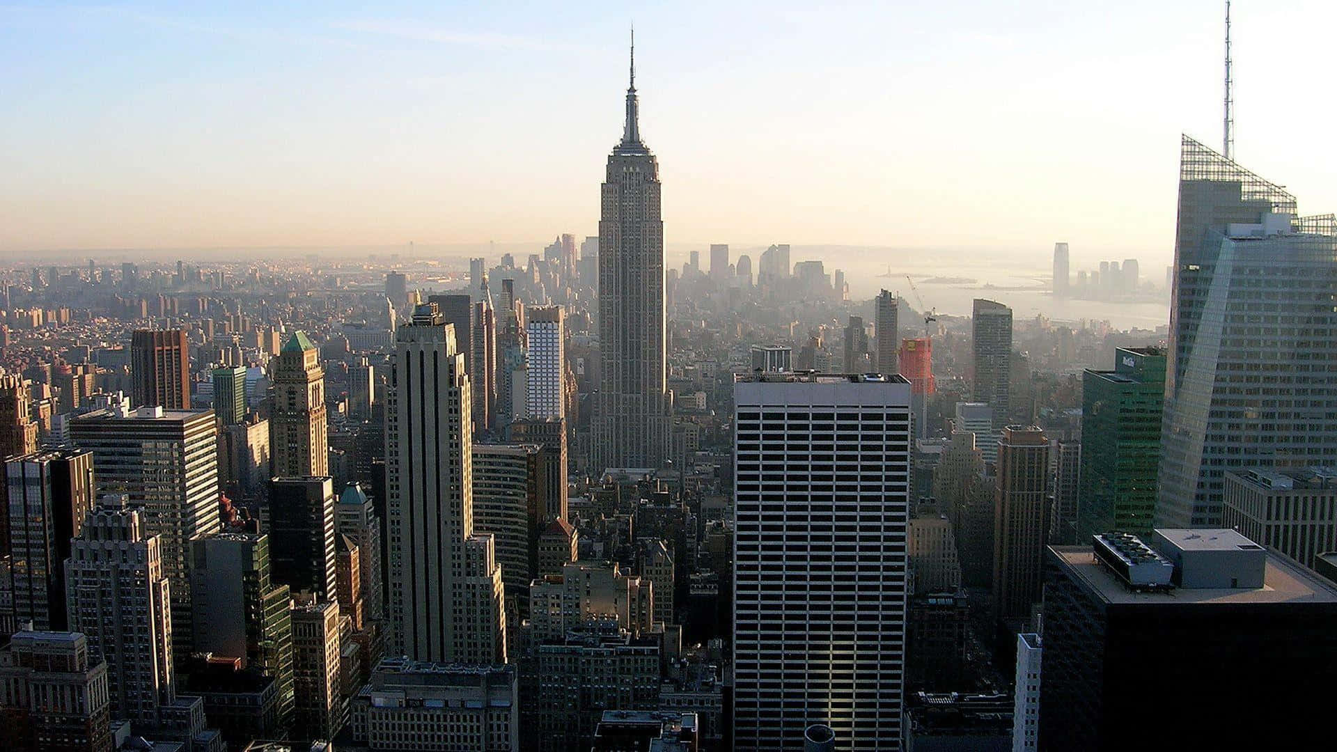 New York 桌布 壁紙 — 紐約市天際線在日出時的鳥瞰圖，帝國大廈聳立在密集的城市建築之上。