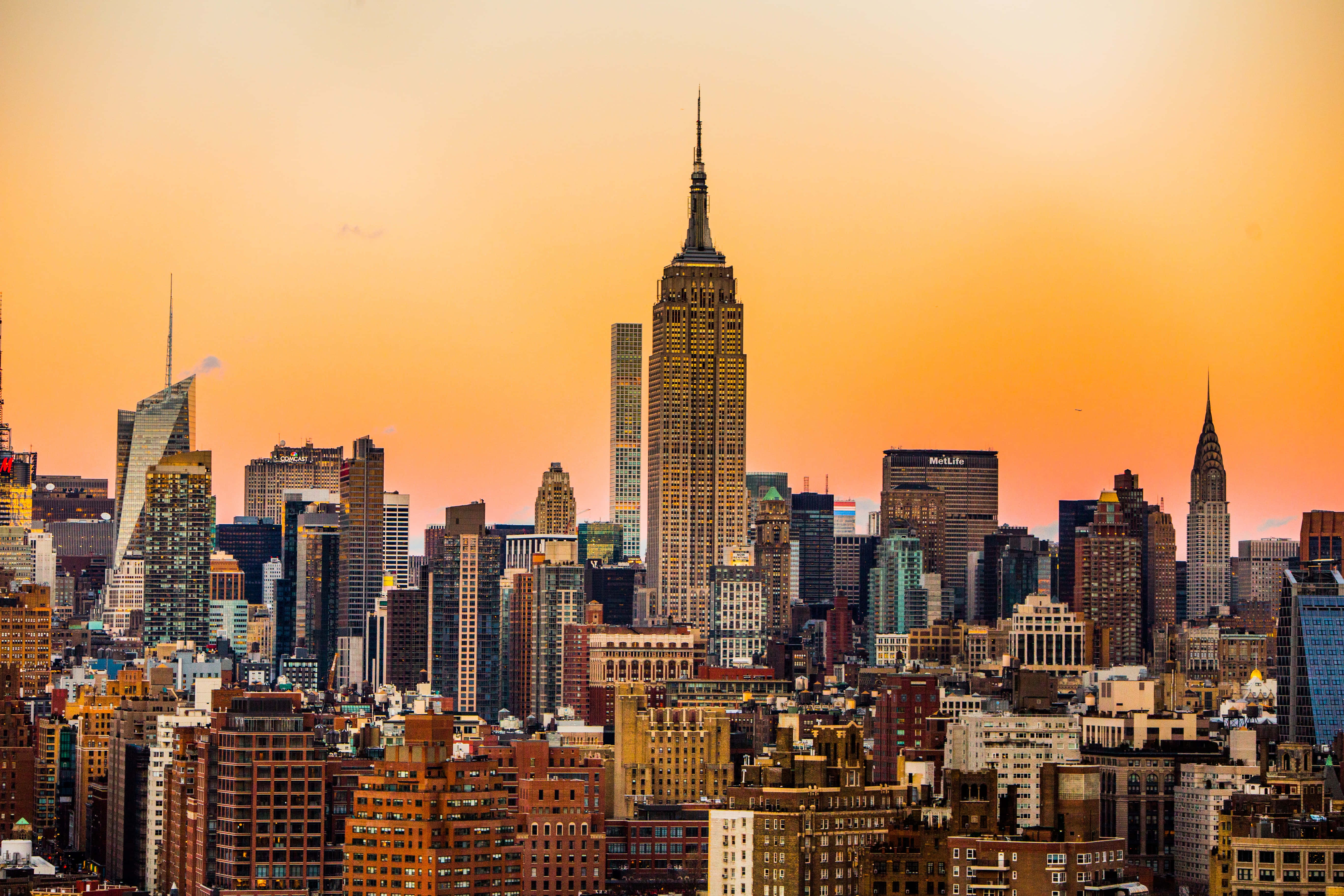 Empire State Building 桌布 壁紙 — 紐約市天際線在日落時分，金色光芒沐浴著包括帝國大廈在內的摩天大樓。