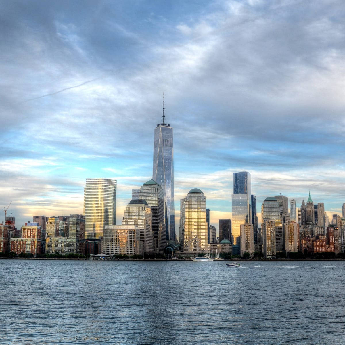 Buildings 桌布 壁紙 — 紐約市天際線在日落時的 panoramatic 景觀，One World Trade Center 高聳於玻璃摩天大樓之上，倒映在水中。