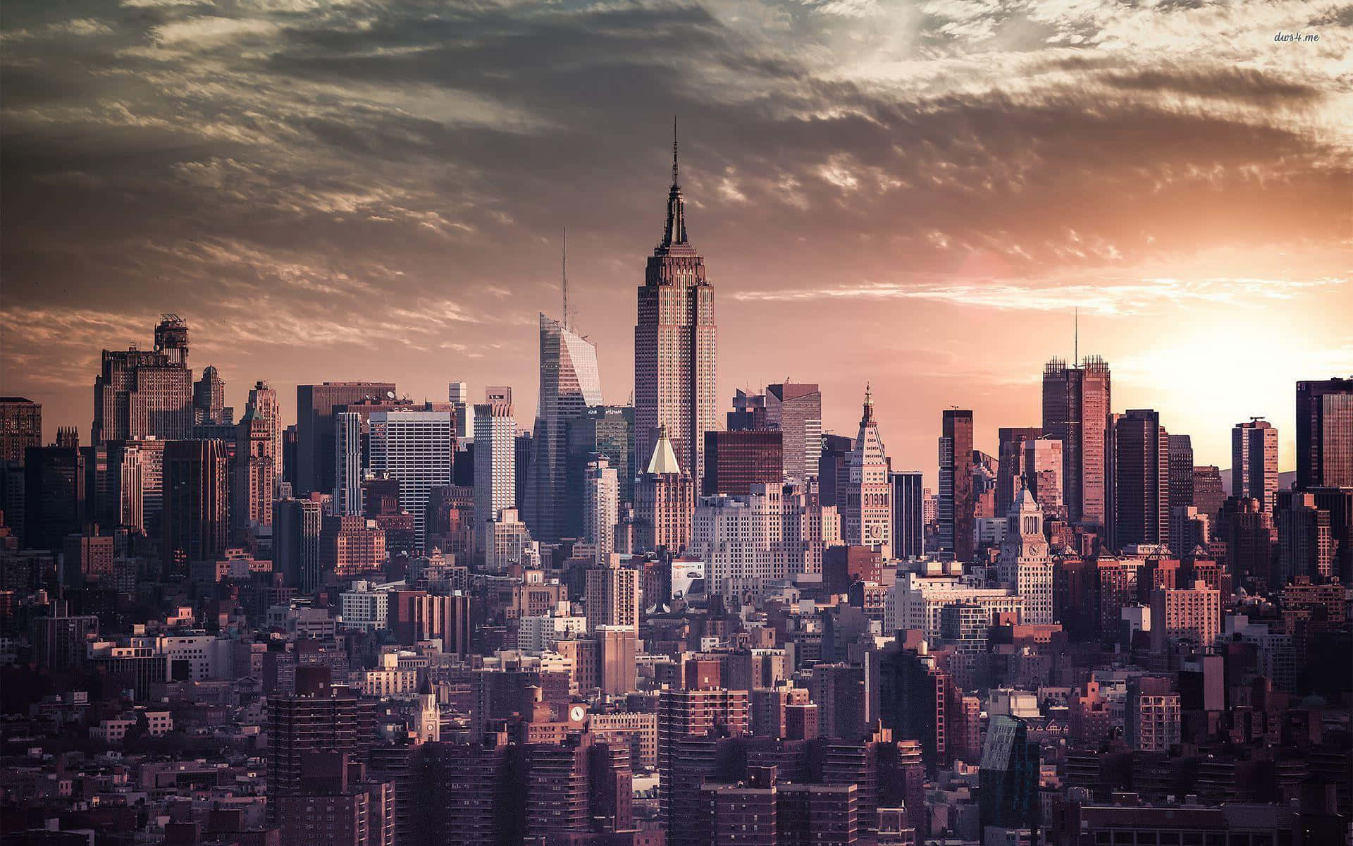 New York 桌布 壁紙 — 紐約市天際線在日落時的 panoram 景觀，金色光線照亮摩天大樓和戲劇性的雲層。
