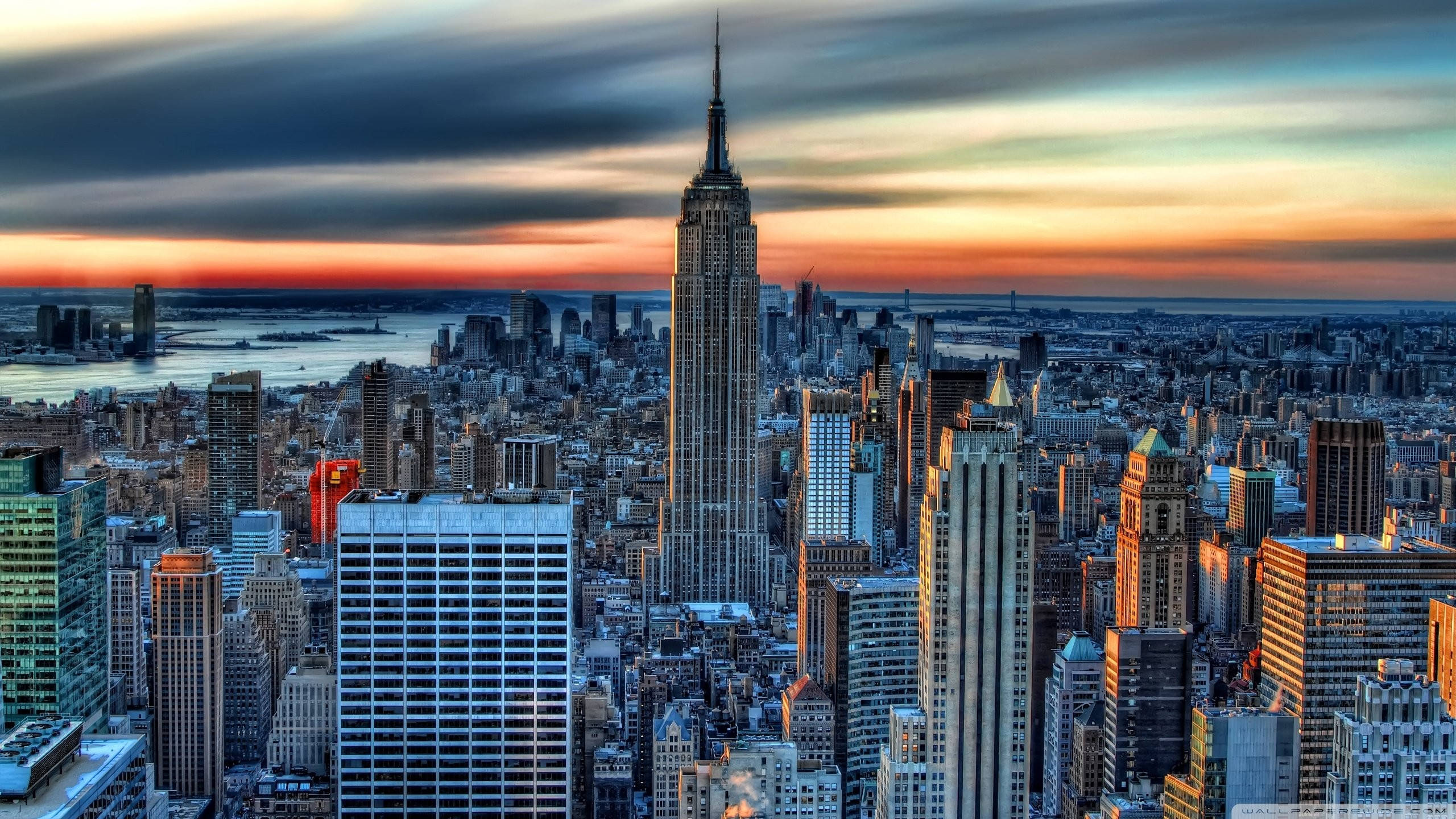 New York City Desktop 桌布 壁紙 — 紐約市天際線在日落時的鳥瞰圖，帝國大廈聳立在摩天大樓和下方水域之上。
