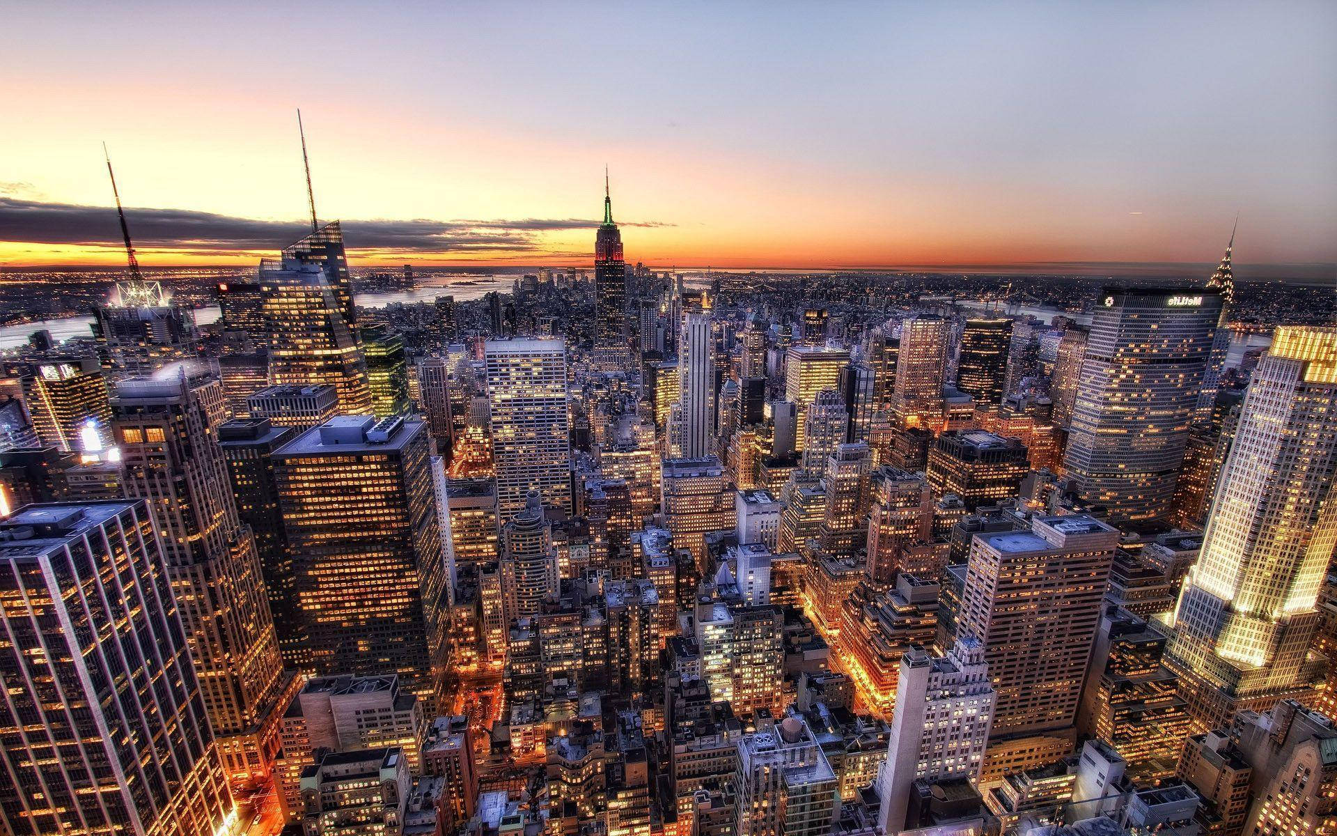 New York City Desktop 桌布 壁紙 — 紐約市天際線在日落時的鳥瞰圖，金色燈光從摩天大樓中閃耀，映襯著漸變的天空。