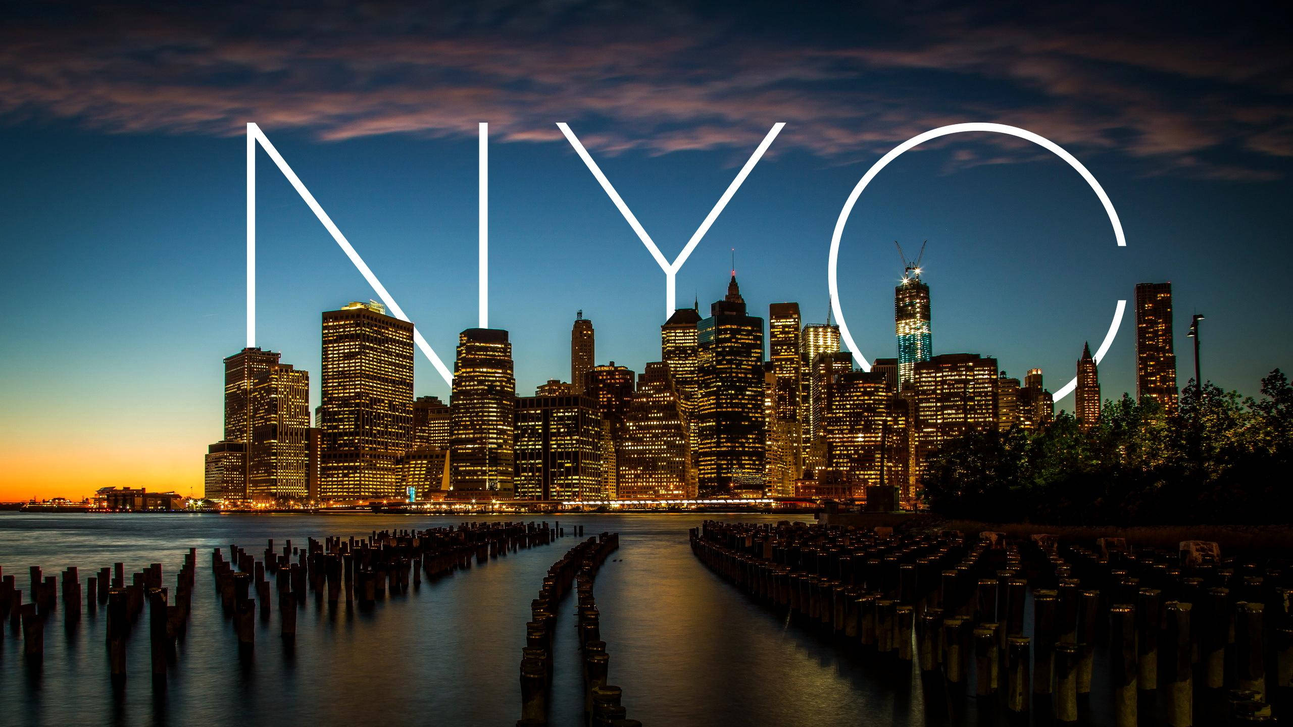 城市 桌布 壁紙 — 紐約市天際線在黃昏時分，發光的「NYC」字母疊加在水面和木樁上。